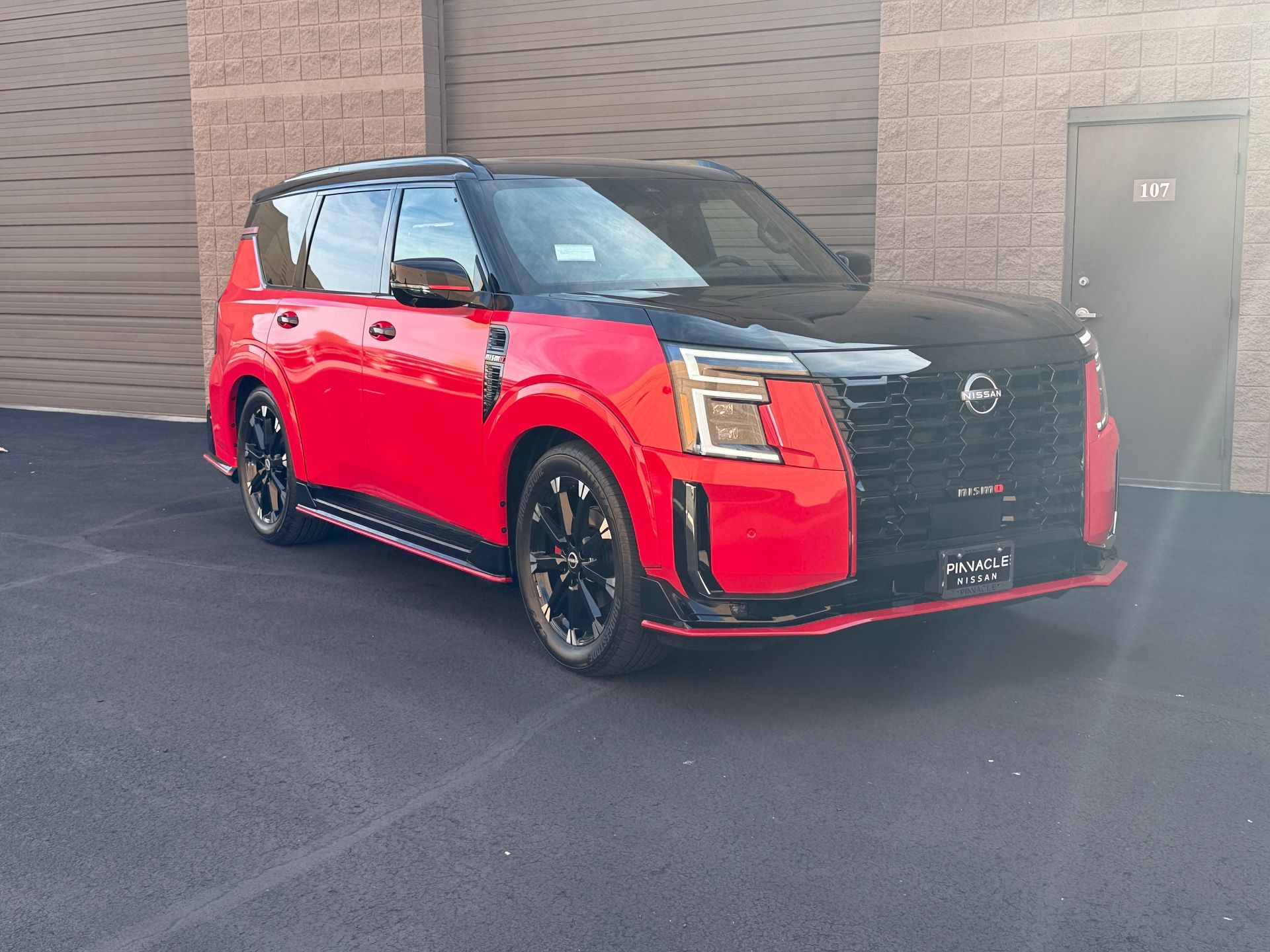 Red Nissan SUV parked outside a building on dark pavement.