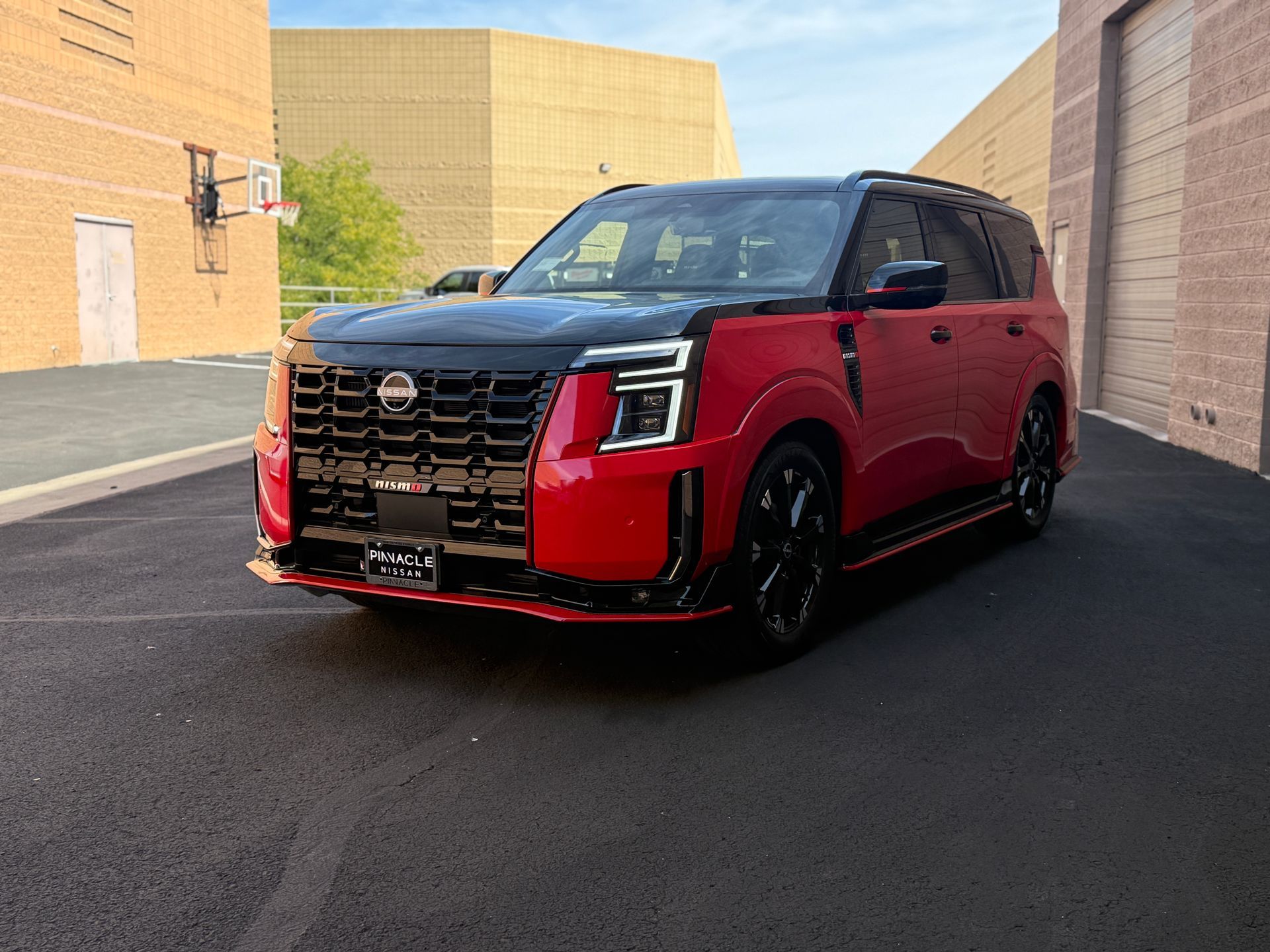 Red SUV parked in a sunlit alley beside tan buildings