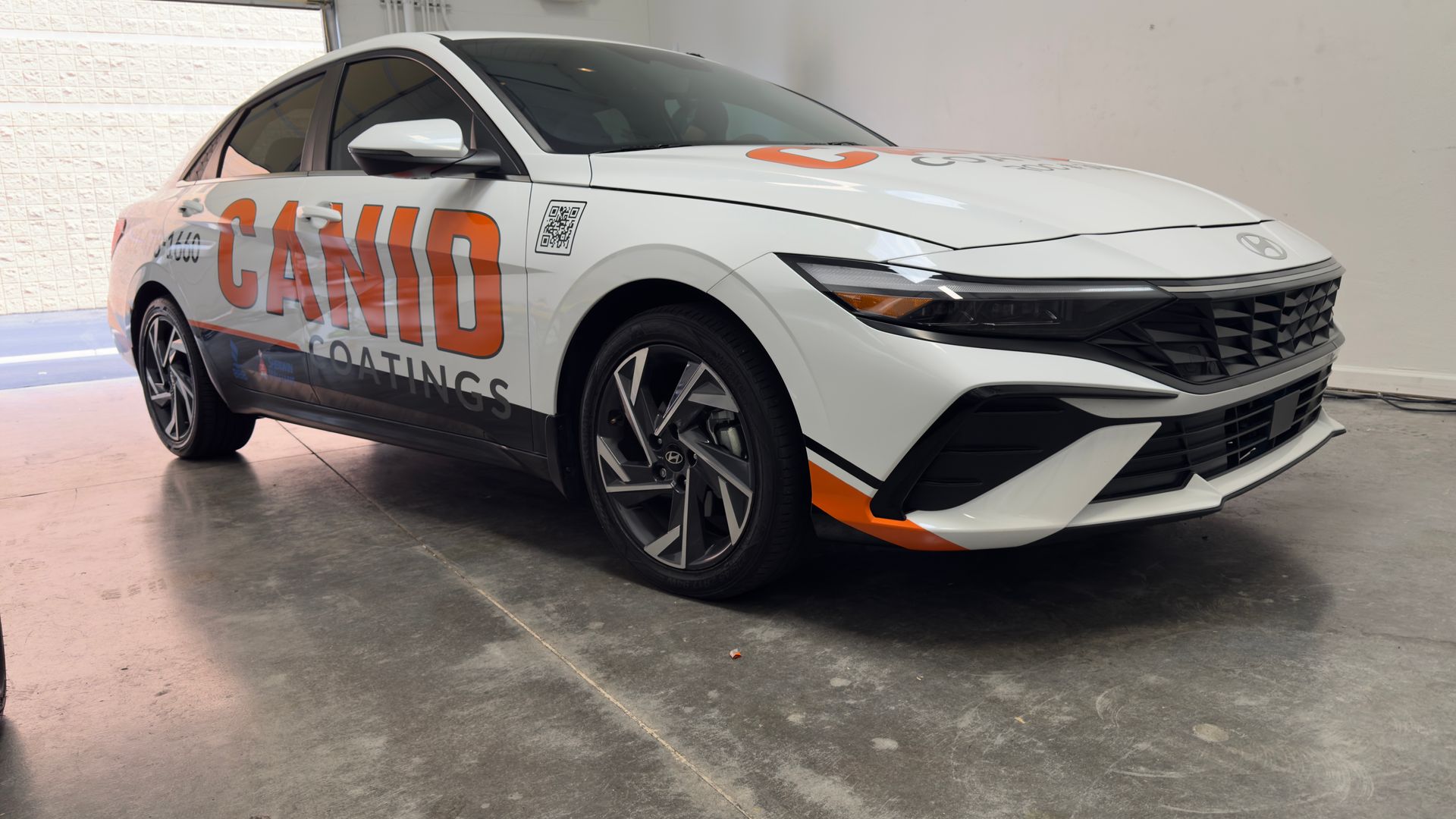 White sedan with CAMIO branding, parked indoors against a plain wall