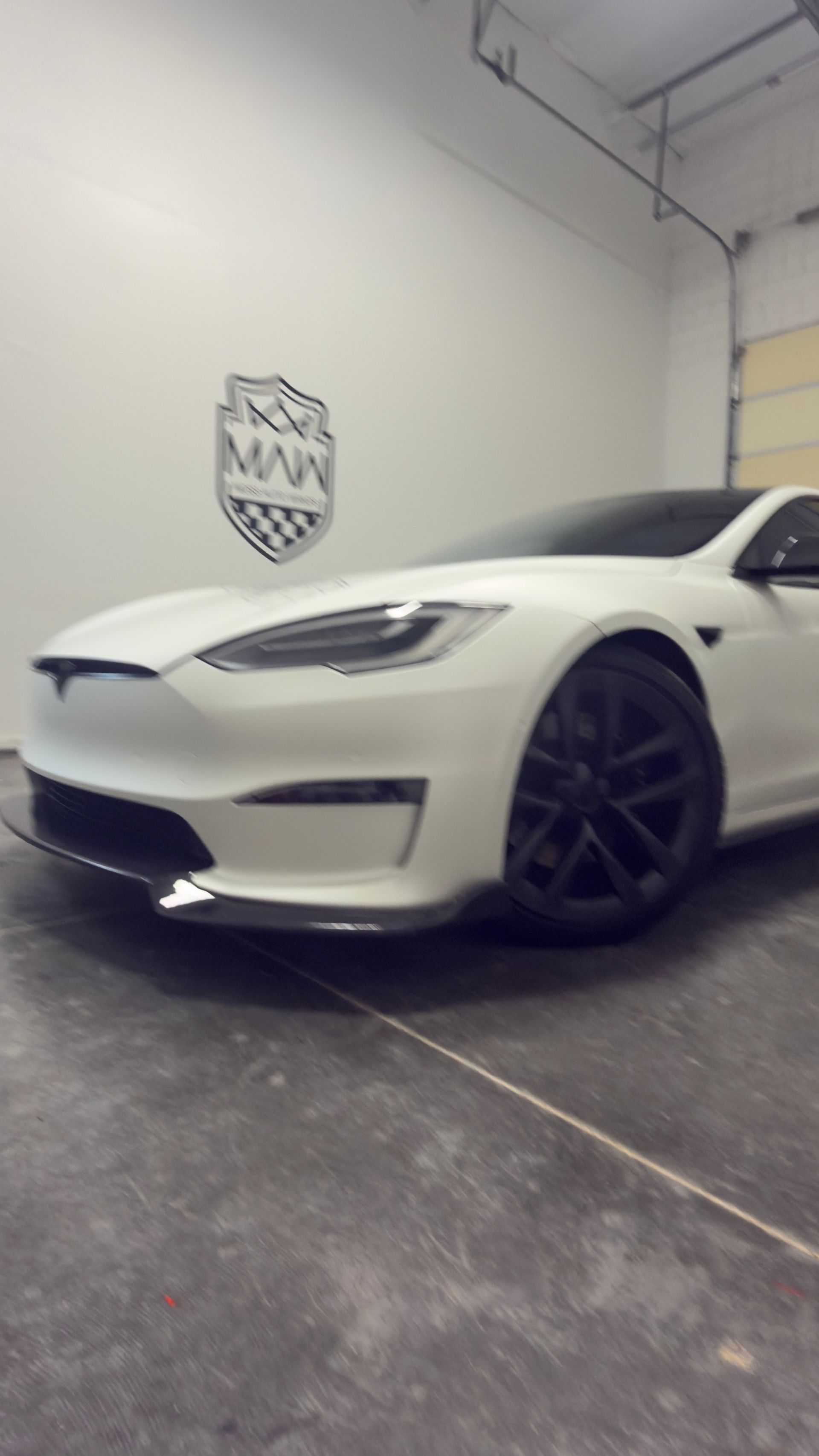 White sports car parked in a garage, shown from the front-left side.
