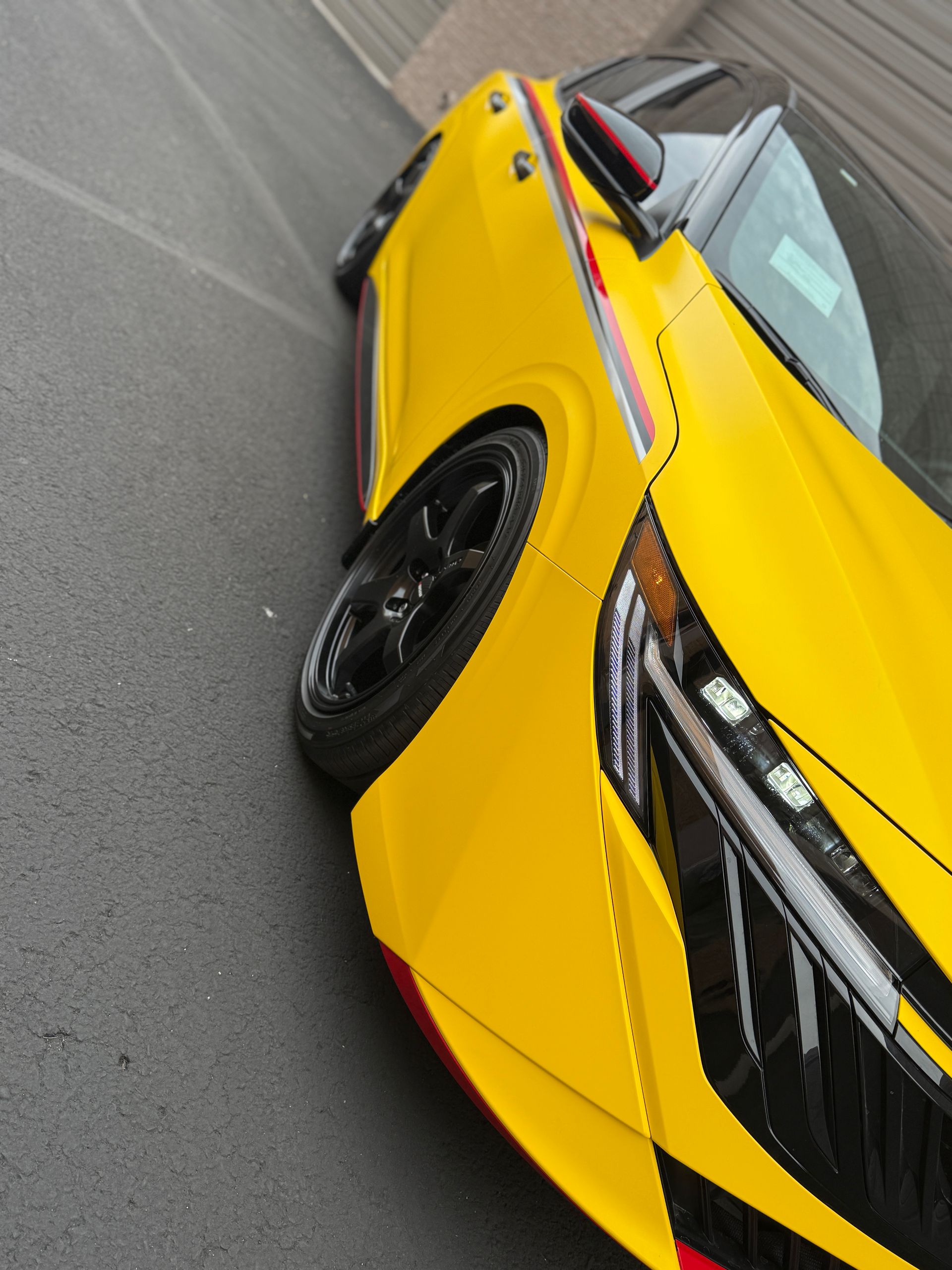 Yellow sports car parked on a road, angled close-up of the front side.
