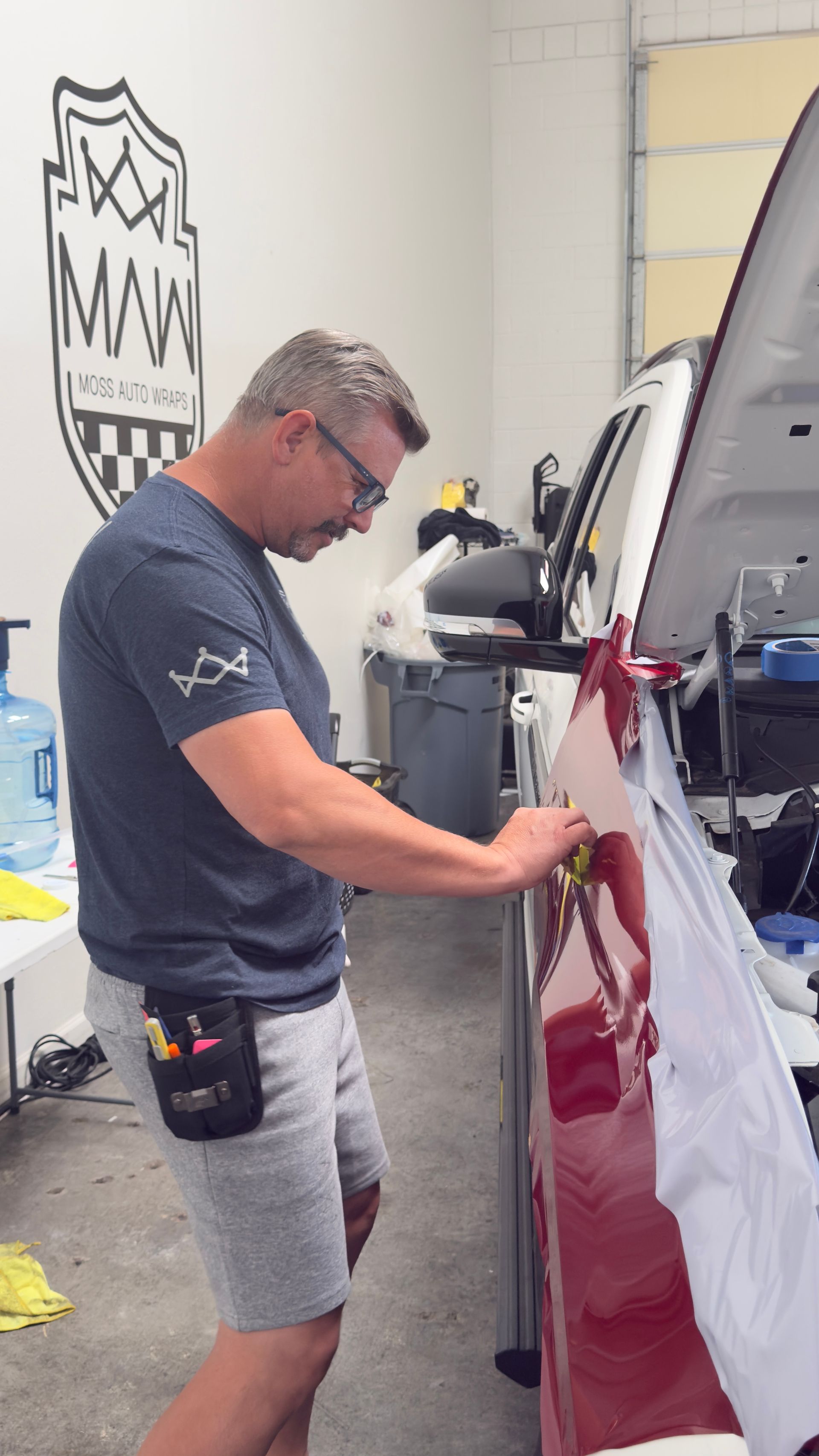 Man polishing a red car door in an auto detailing shop