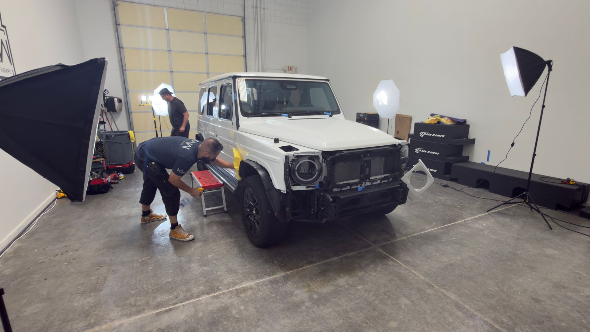 White off-road SUV in a studio with two photographers and lighting equipment