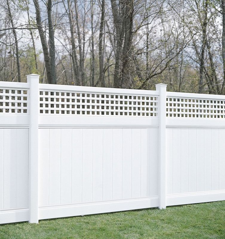 White vinyl fence with lattice top, set in a grassy yard with trees in the background.