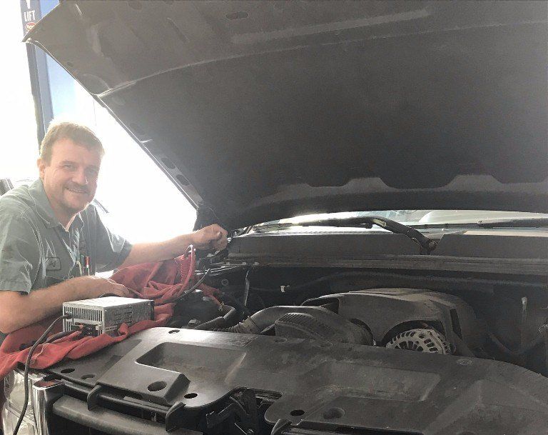 Man working on a car engine under the open hood.