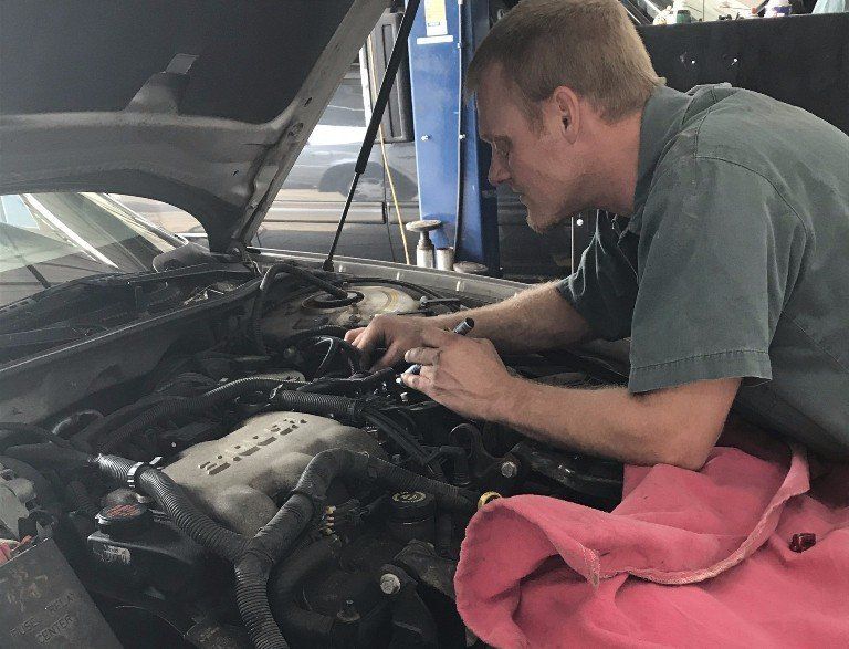 Mechanic working on car engine in a garage.