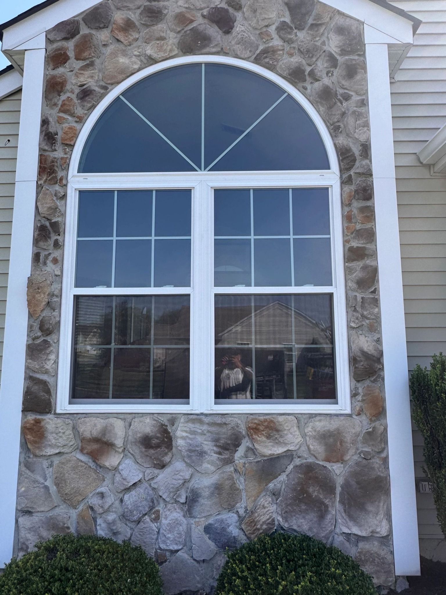 Stone exterior with a large window; a half-circle top and grid pattern.