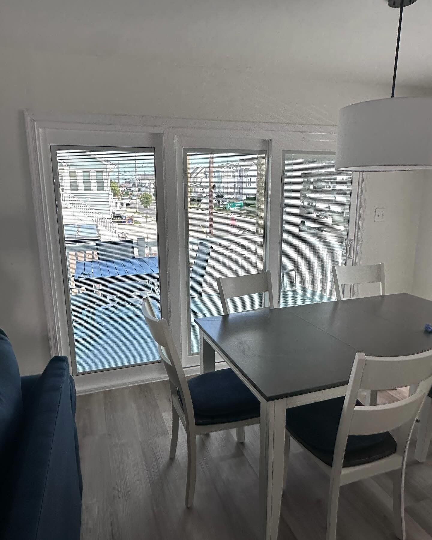 Dining room with three windows overlooking a waterfront. A table and chairs sit near the windows.