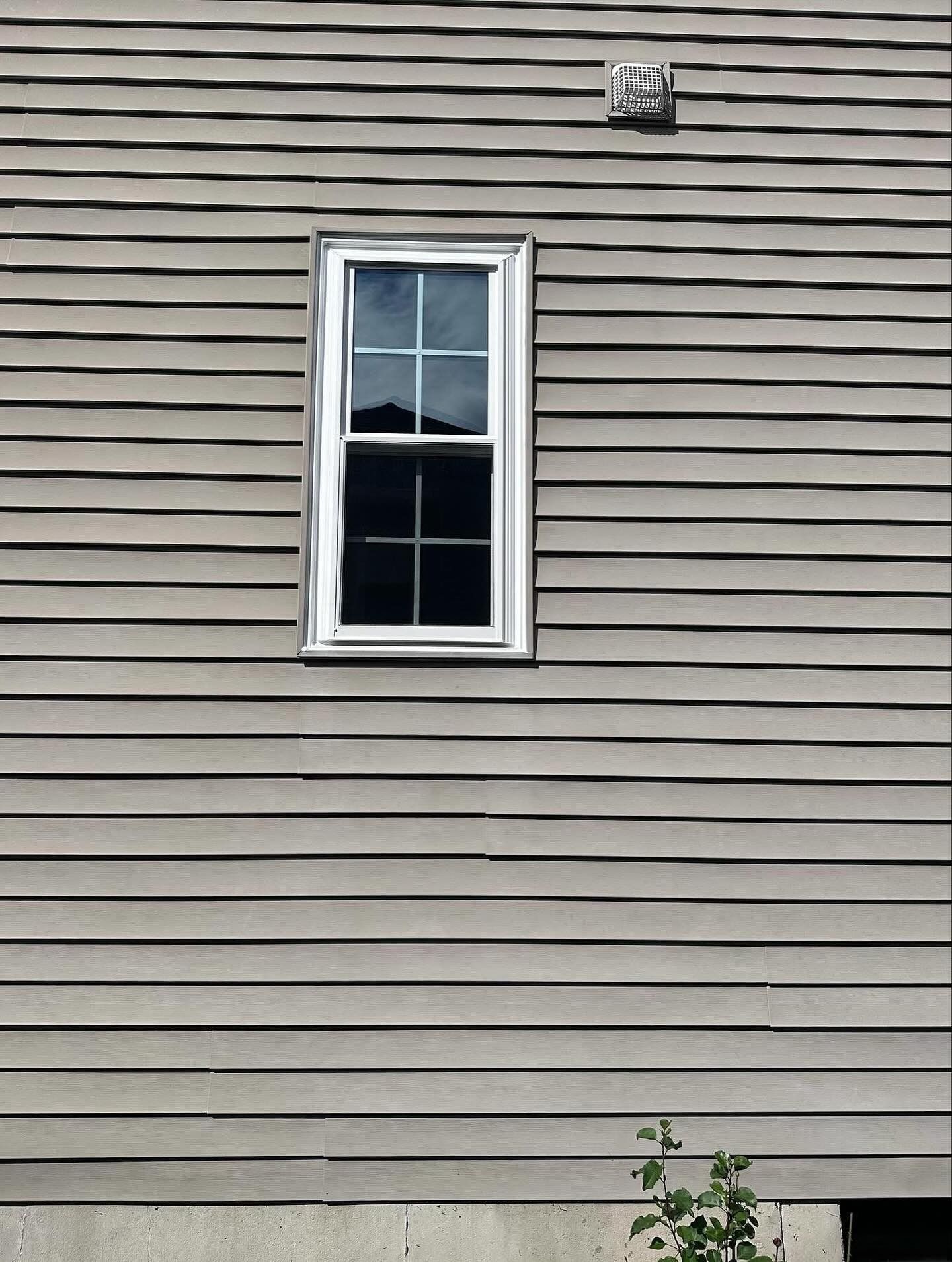 Window in a gray-sided building with horizontal clapboard siding.
