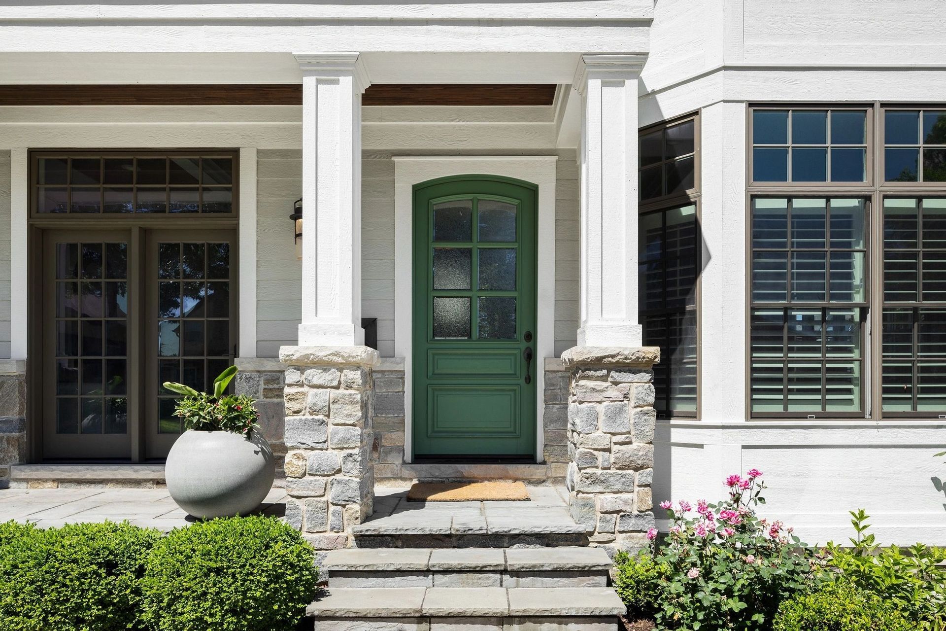 Green front door with stone columns and steps.