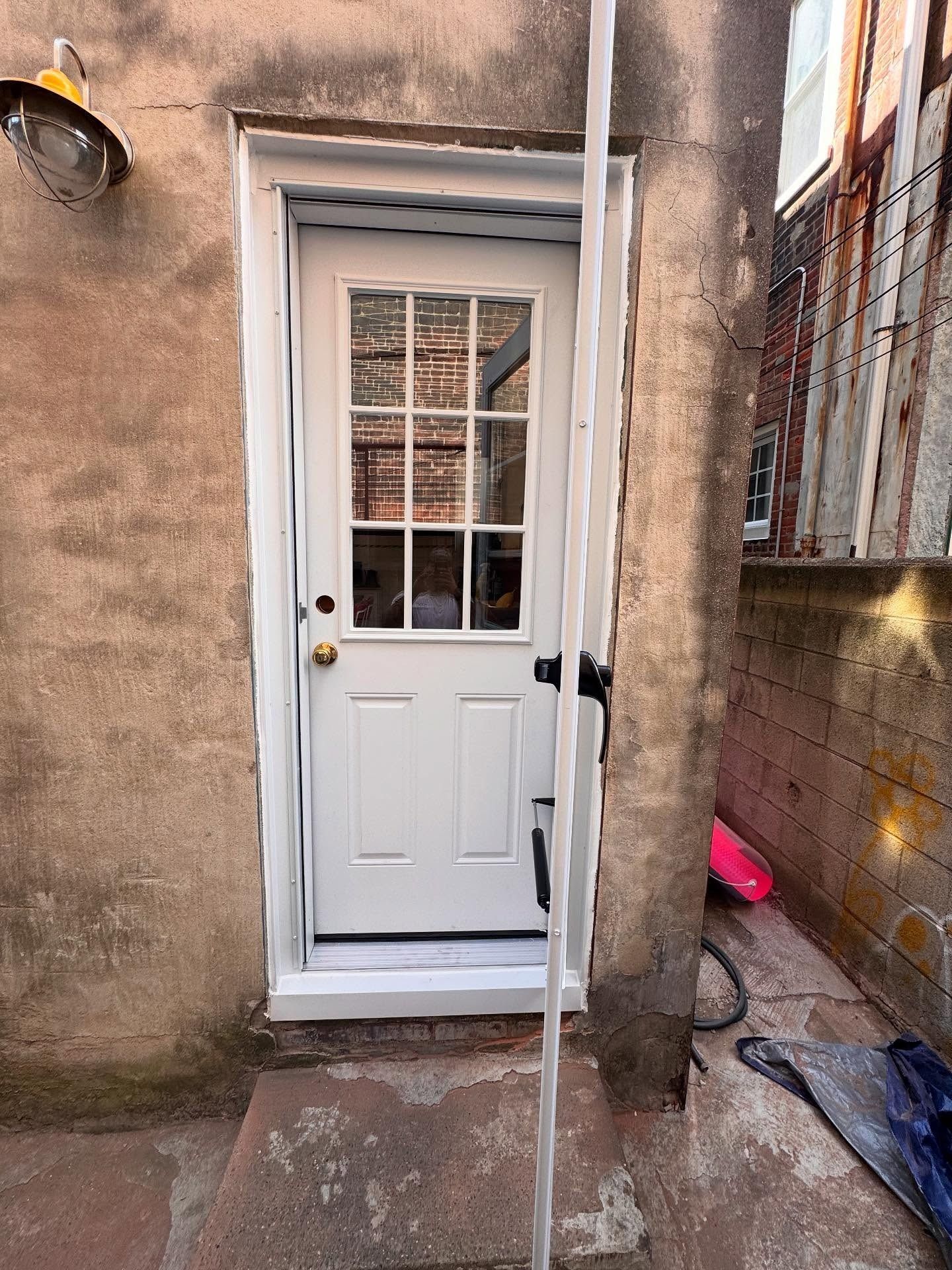 White door with glass panes in a weathered brick building exterior.