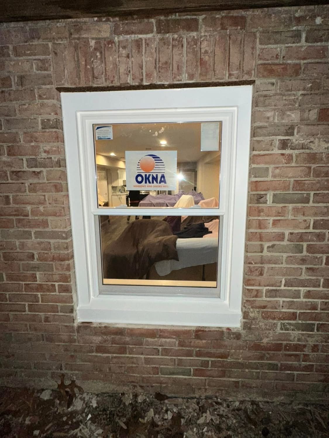 White-framed window in a brick wall, with a sticker visible on the glass and some interior details.