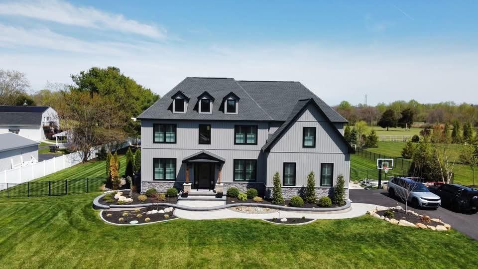 Gray two-story house with black trim, gray roof, three dormers, and well-manicured lawn.