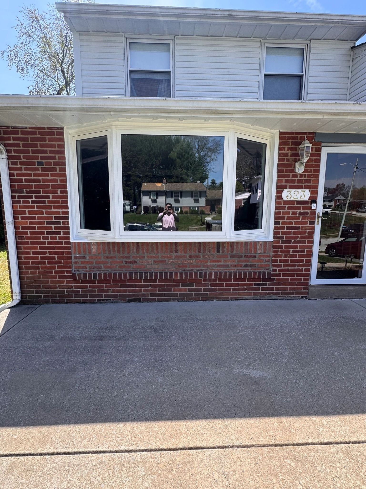 Brick house exterior with a large front window, a doorway, and a concrete patio.
