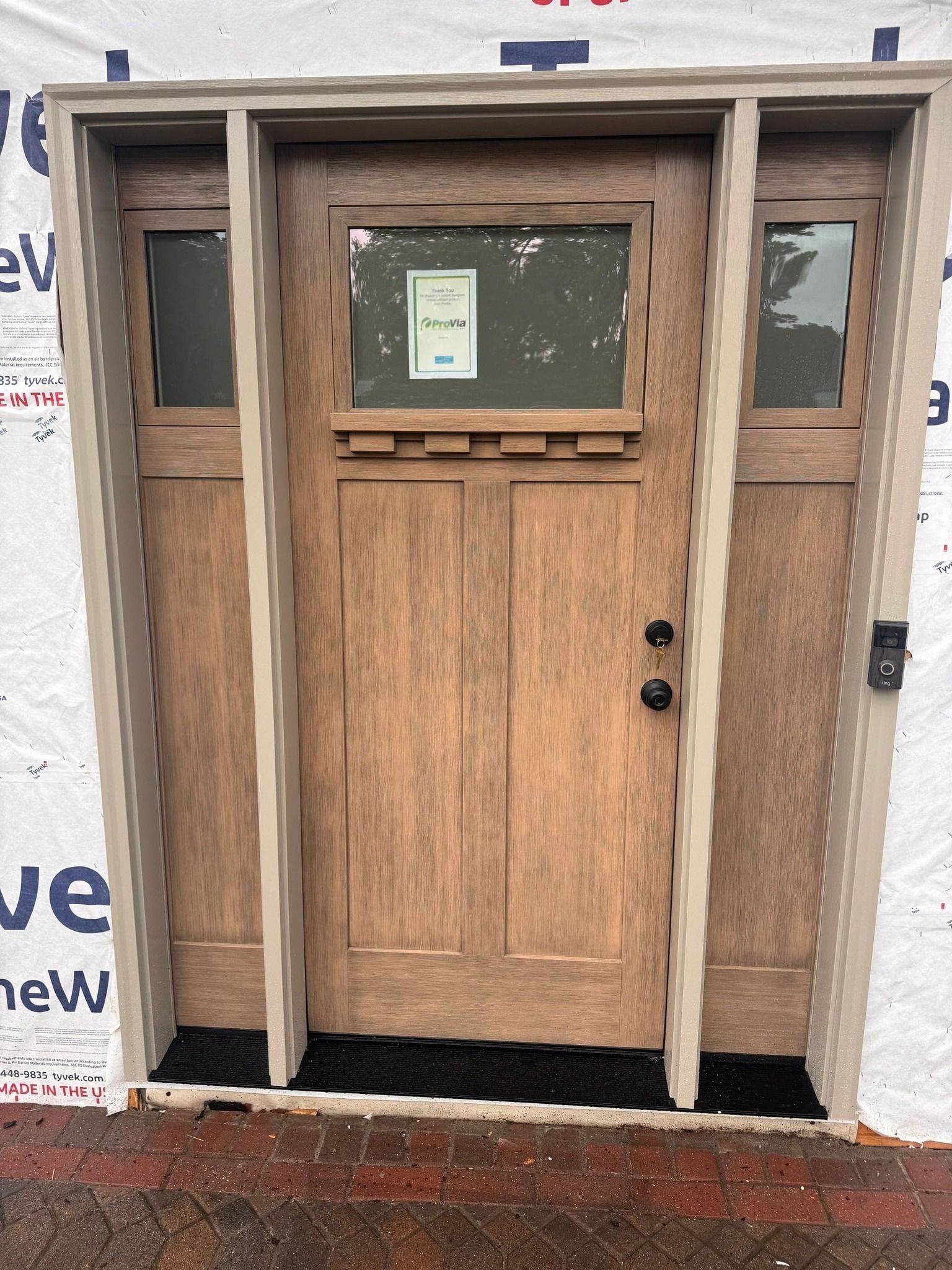 Wooden front door with sidelights, beige trim, new construction.