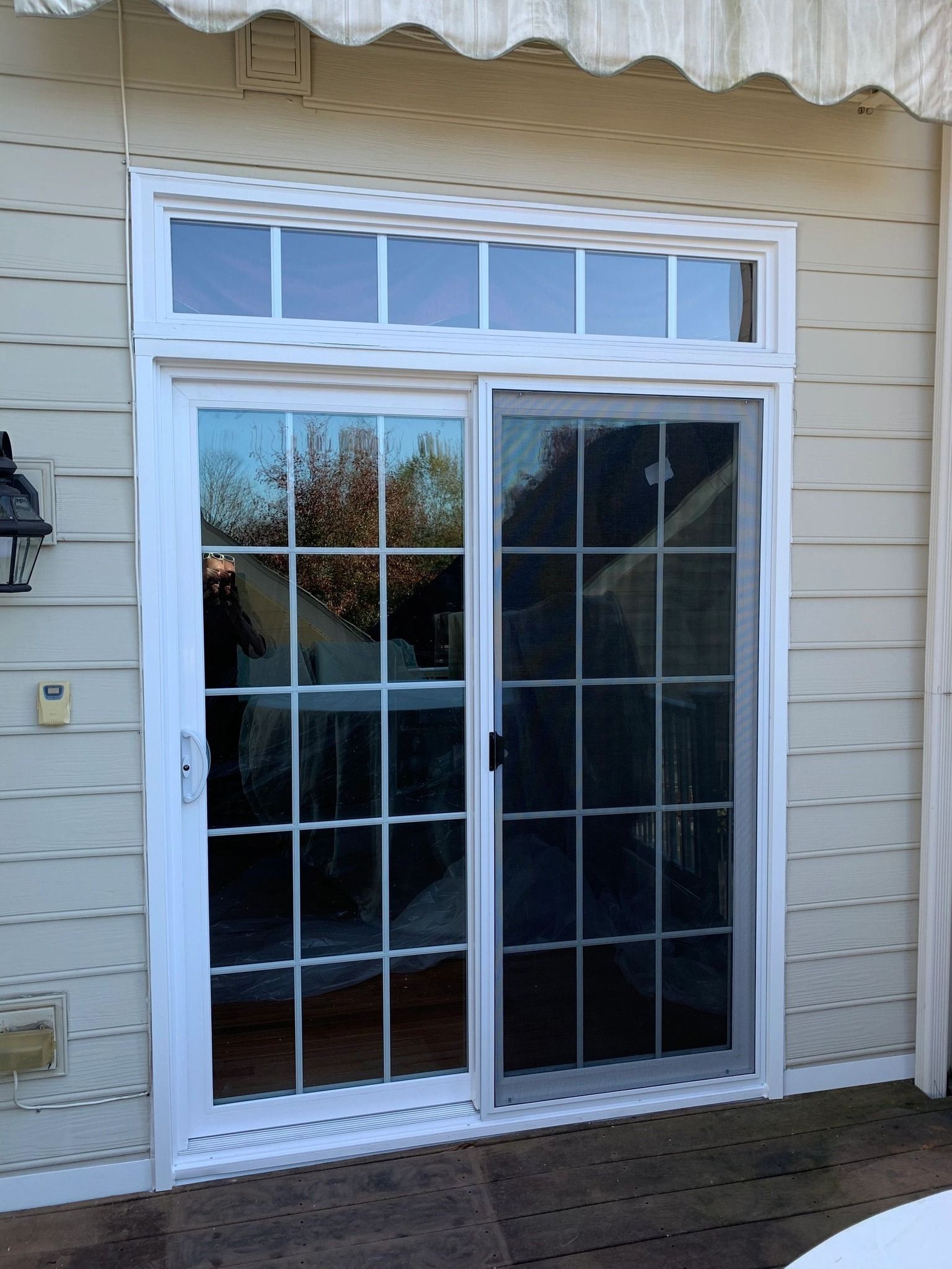 Sliding glass door with white frame, screen, and grid, with an upper window.