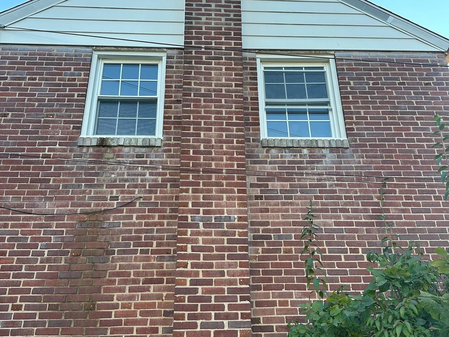 Red brick wall with two windows and a central chimney.