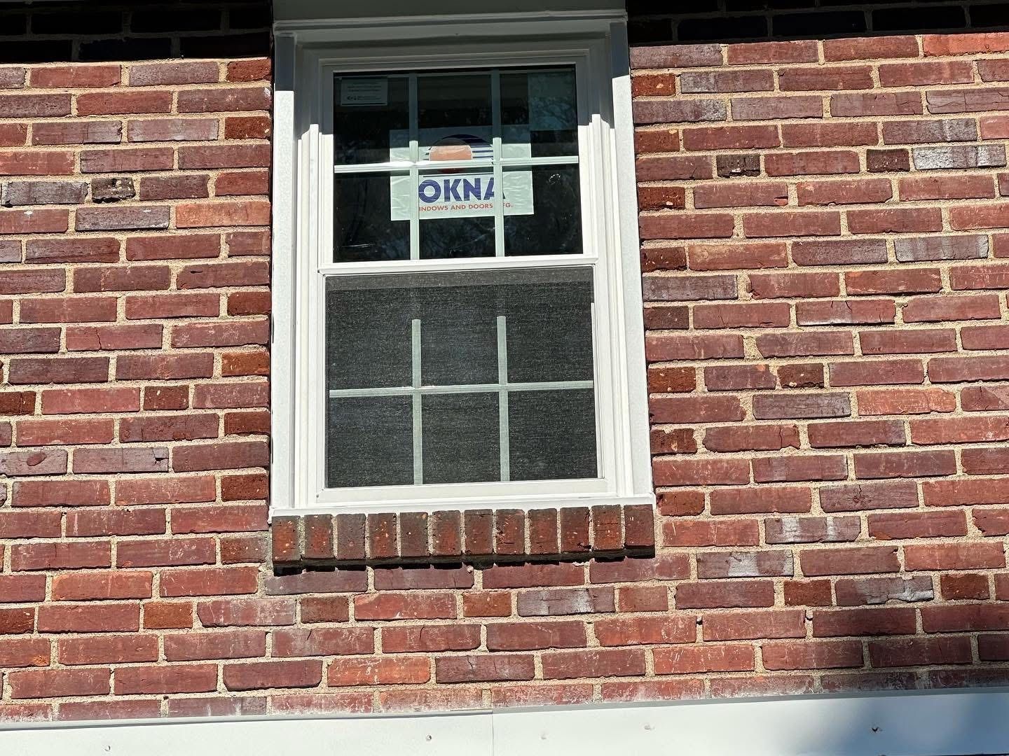 Window in a red brick wall. The window has white trim and a divided pane.