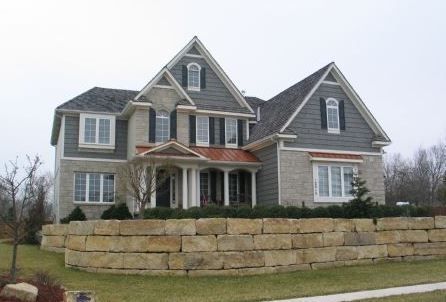 A large house with a stone wall in front of it