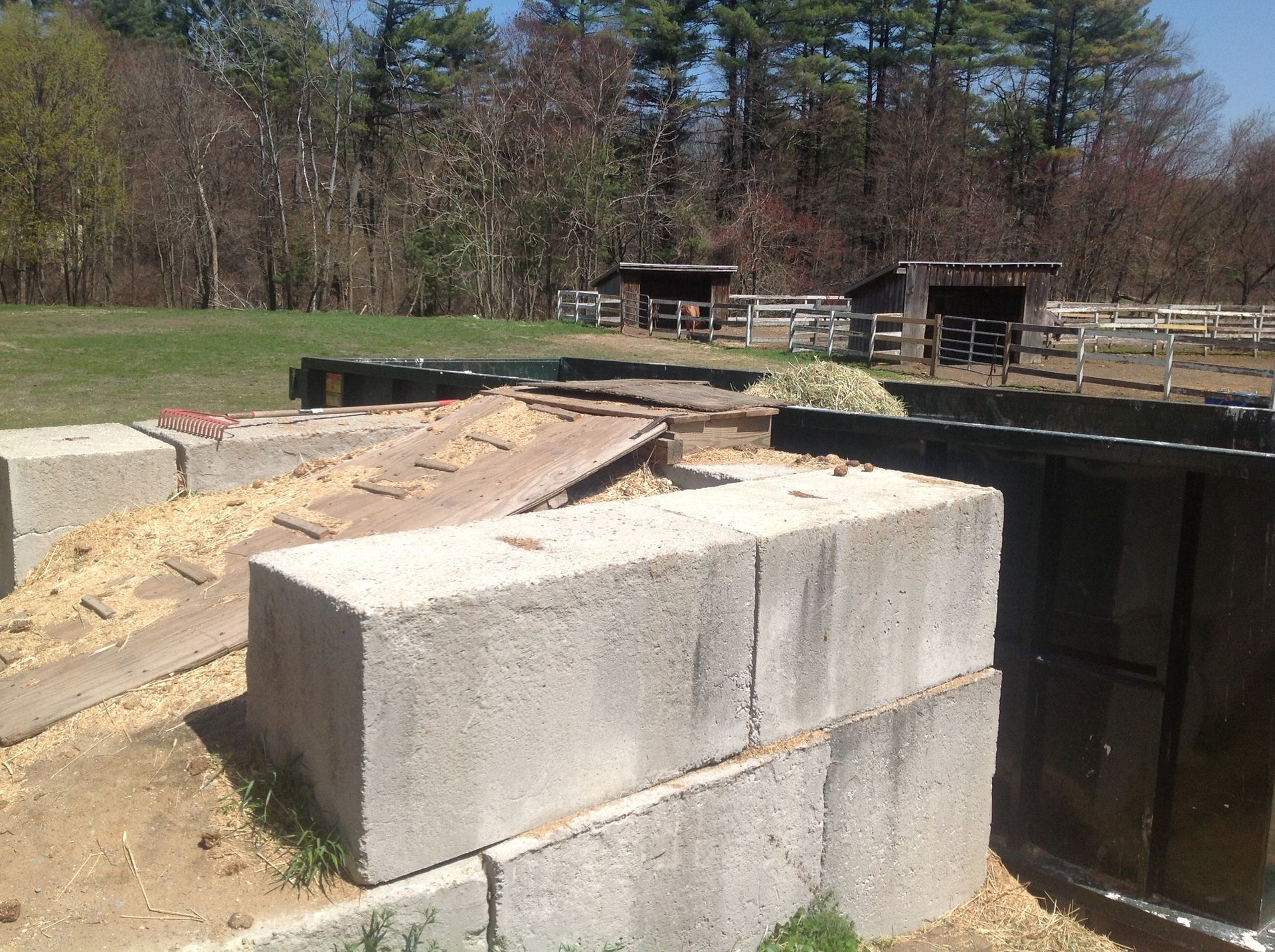 Concrete blocks form a ramp structure, possibly for livestock, with stalls and a pasture visible in the background.
