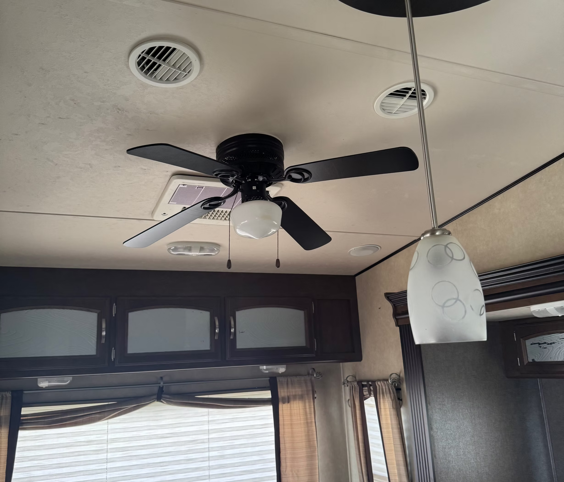 Ceiling fan with lights in a room with windows and a hanging pendant lamp
