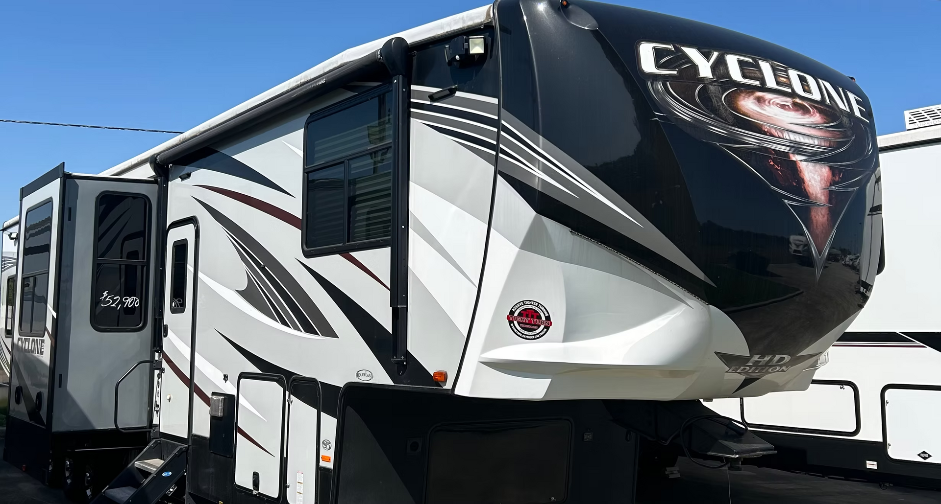 Black and white Cyclone fifth-wheel RV trailer parked outdoors under a blue sky