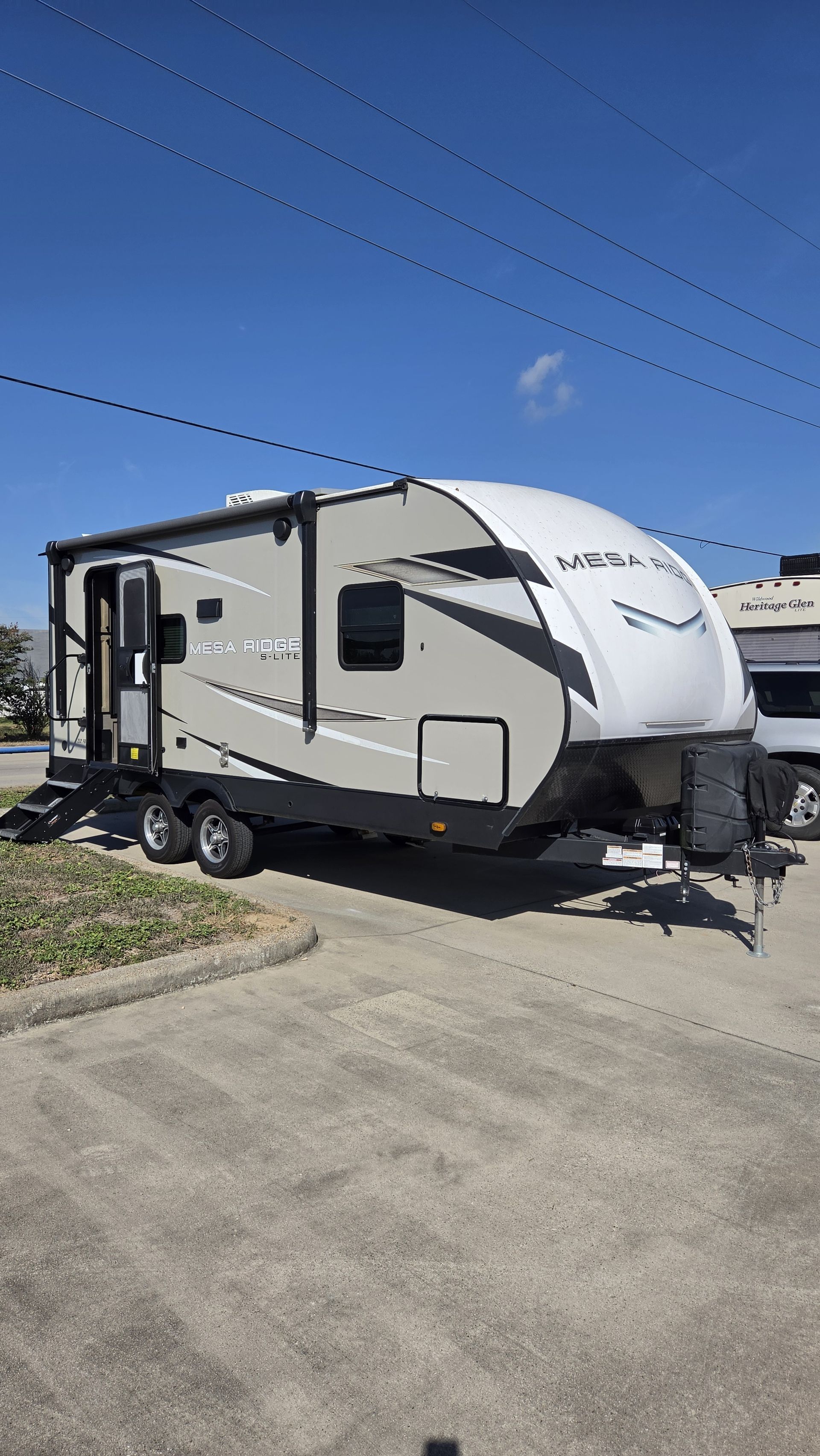 White travel trailer parked on a driveway under a clear blue sky.