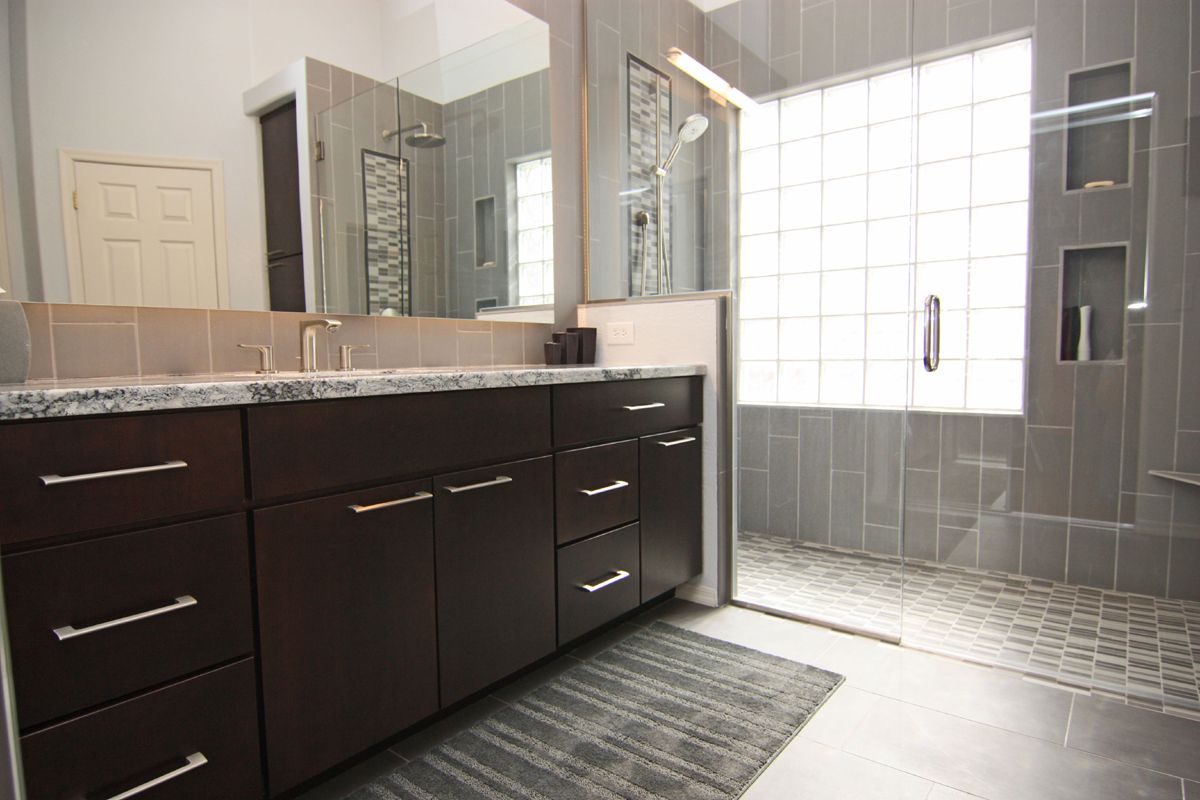 A bathroom with two sinks and a walk in shower.