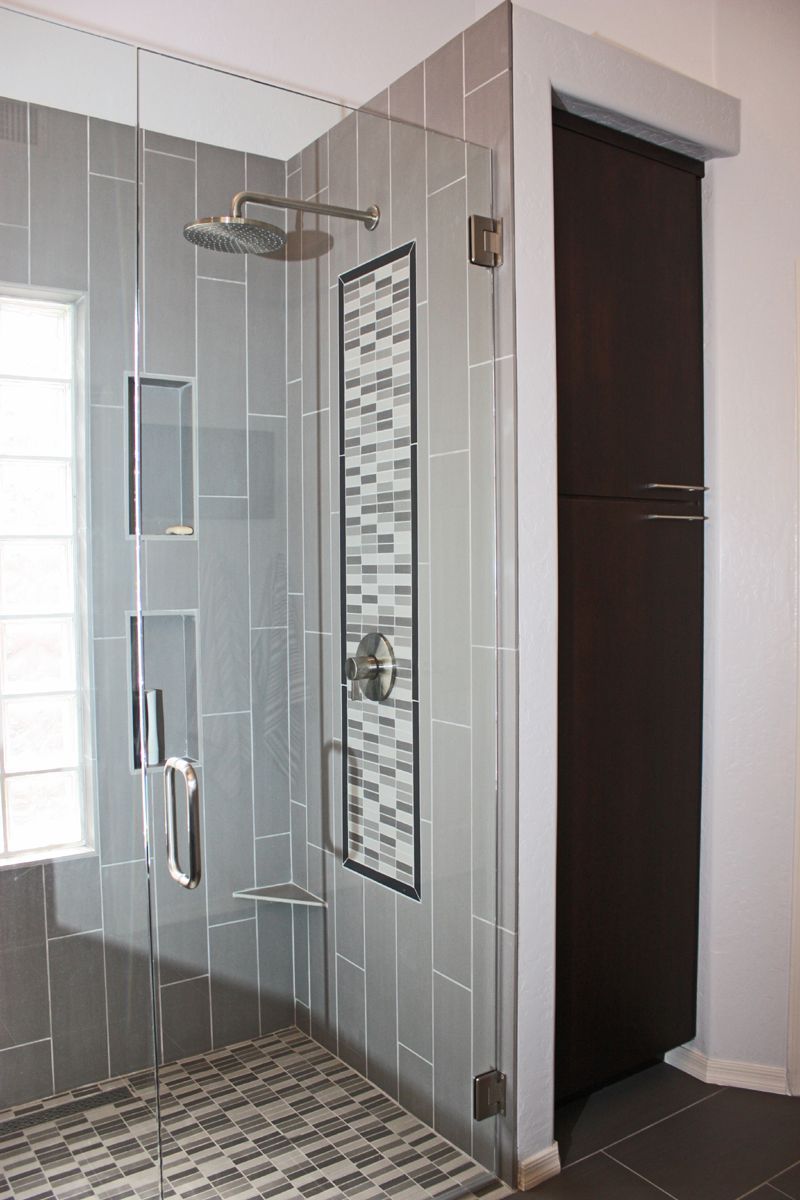 A bathroom with a walk in shower with a glass door and a window.