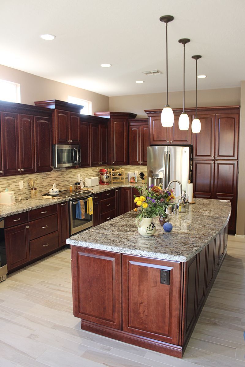 A kitchen with wooden cabinets, granite countertops, stainless steel appliances and a large island.