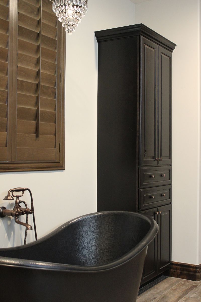 A bathroom with a black tub and black cabinets