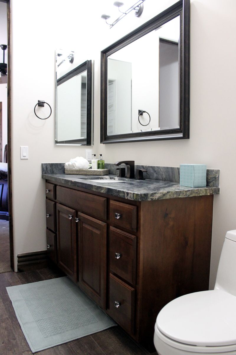 A bathroom with two sinks, two mirrors and a toilet.