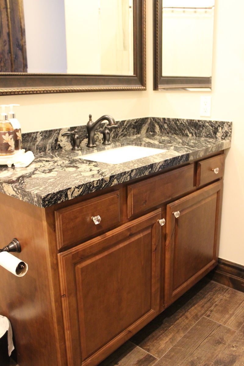 A bathroom with a sink, mirror, and wooden cabinets.