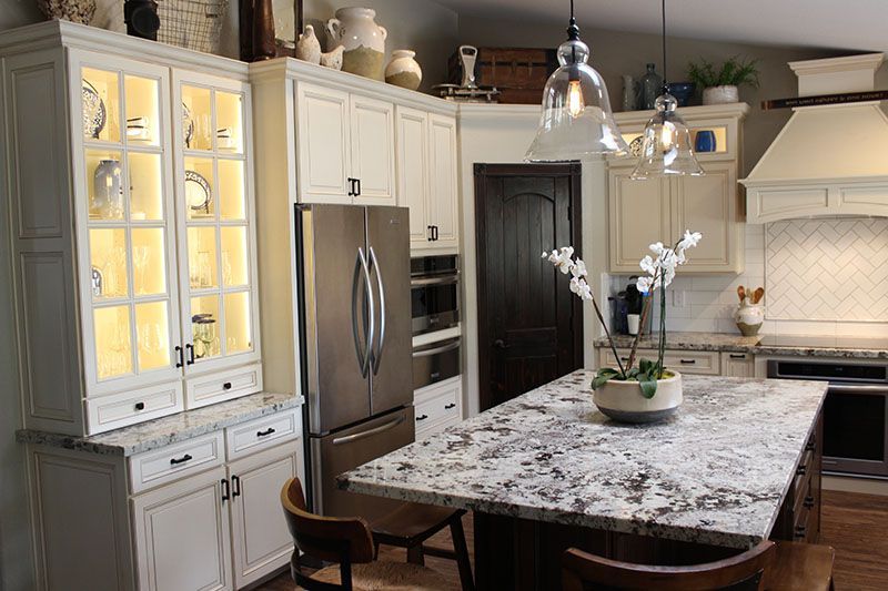 A kitchen with white cabinets, granite countertops, stainless steel appliances and a large island.