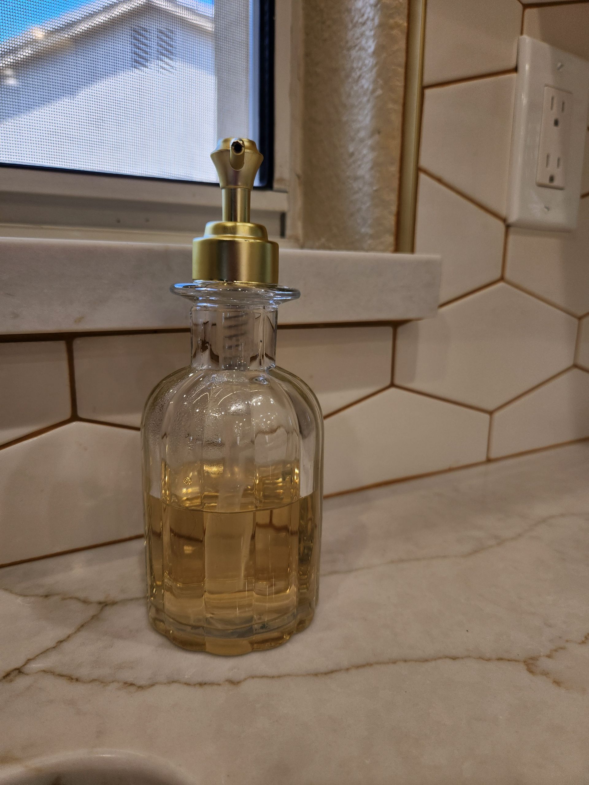 A soap dispenser is sitting on a counter next to a window.