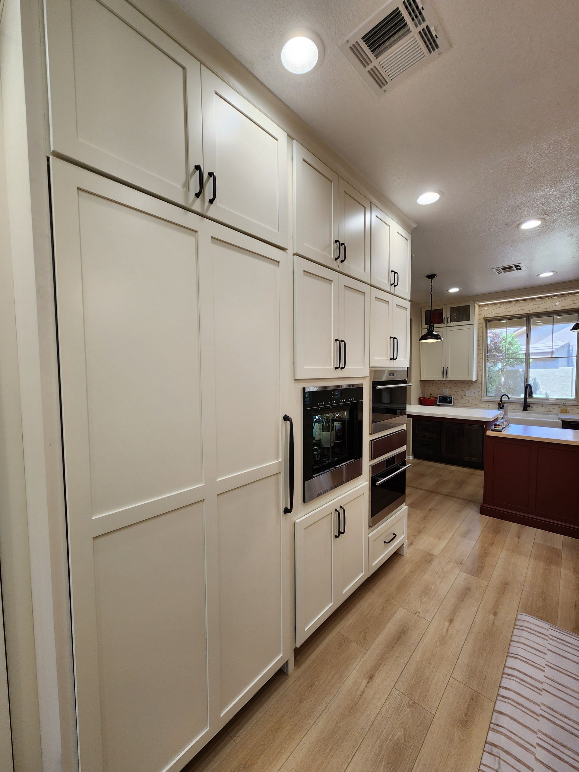 A kitchen with white cabinets, stainless steel appliances, and hardwood floors.