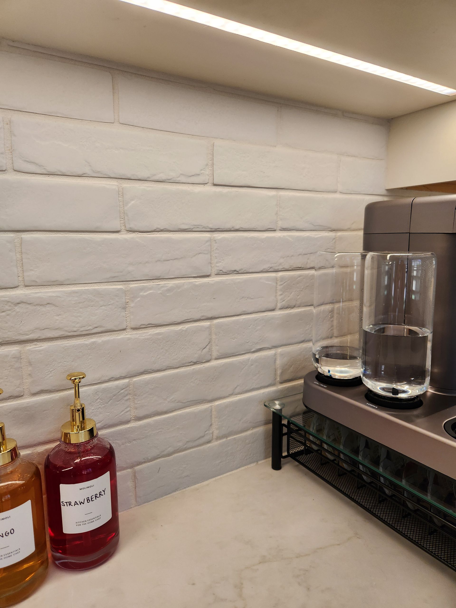 A kitchen counter with two bottles of soap and a coffee maker.