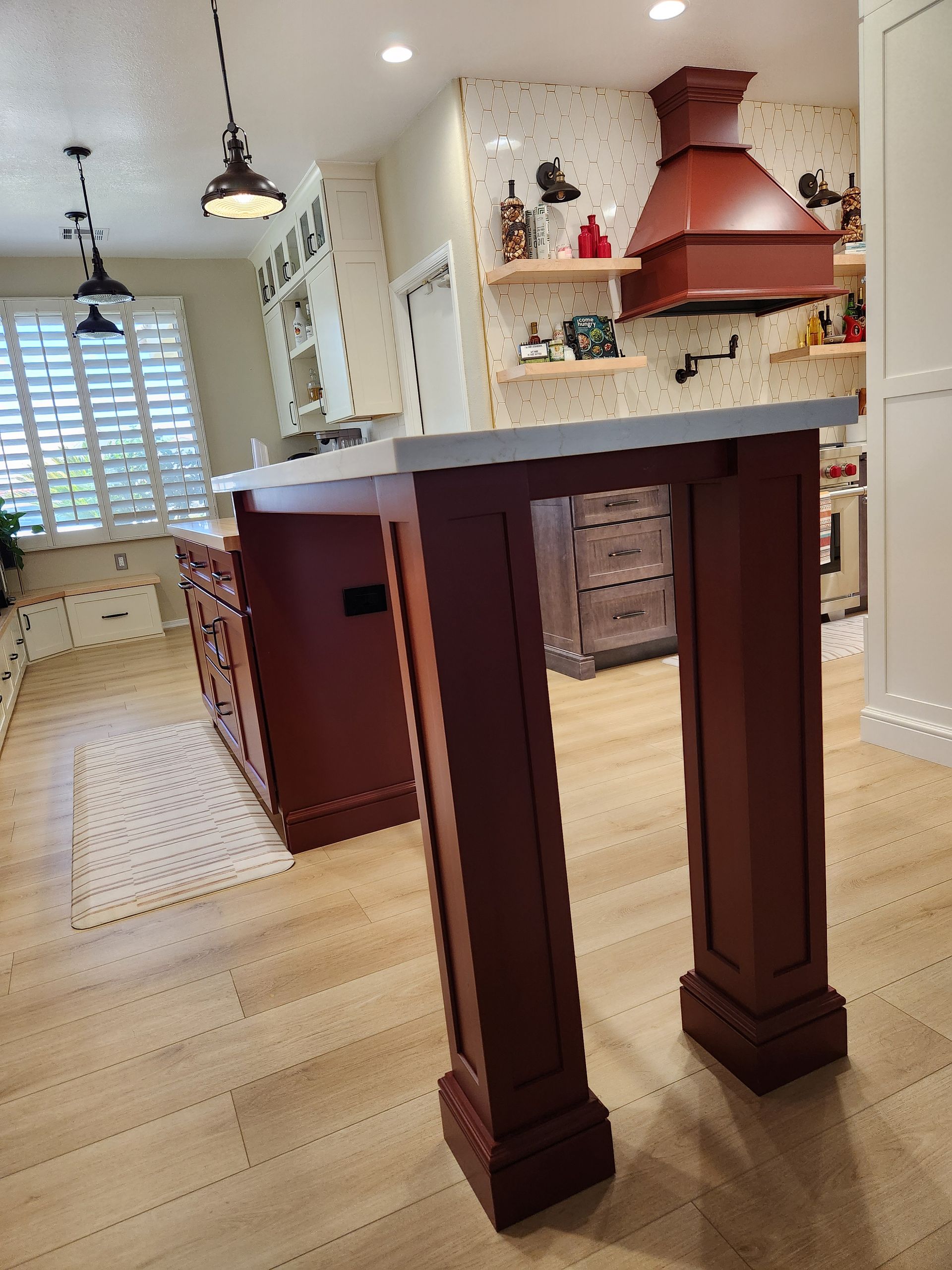 A kitchen with a large island and a red hood