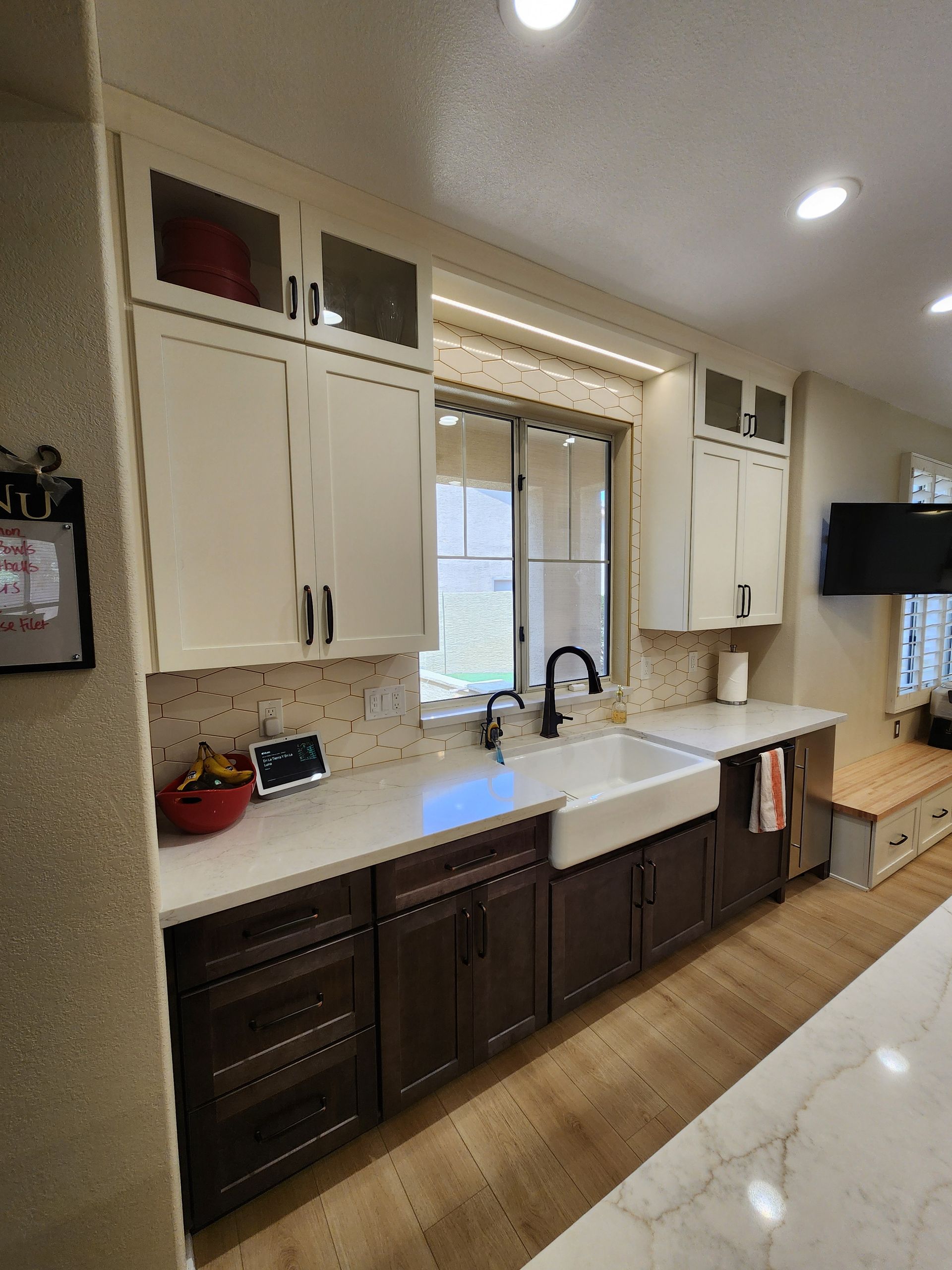 A kitchen with a sink, cabinets, counter tops, and a window.