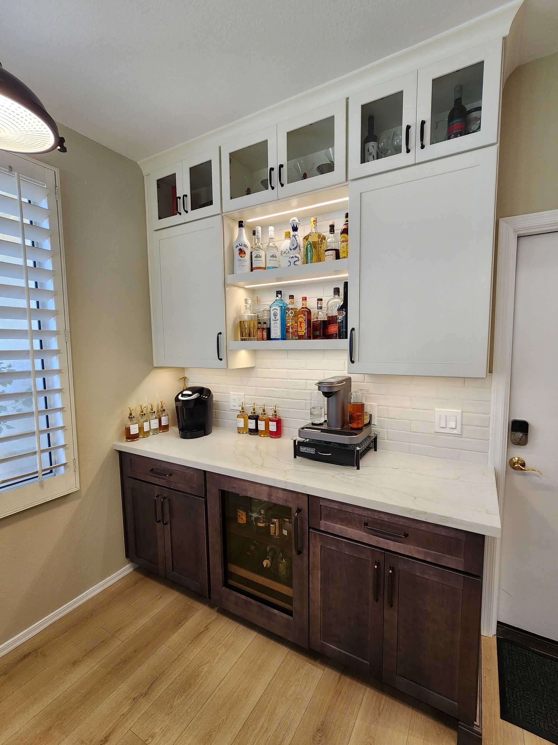 A kitchen with lots of cabinets and bottles on the counter