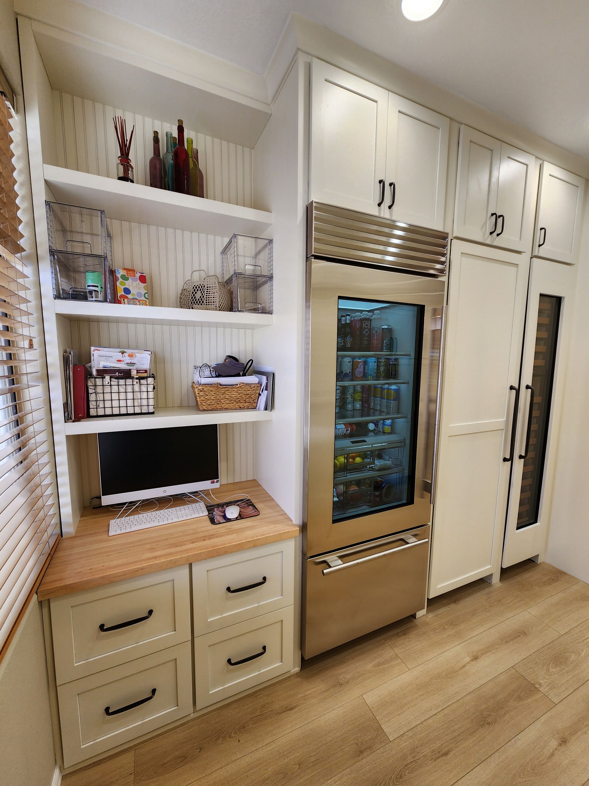 A kitchen with white cabinets and a stainless steel refrigerator
