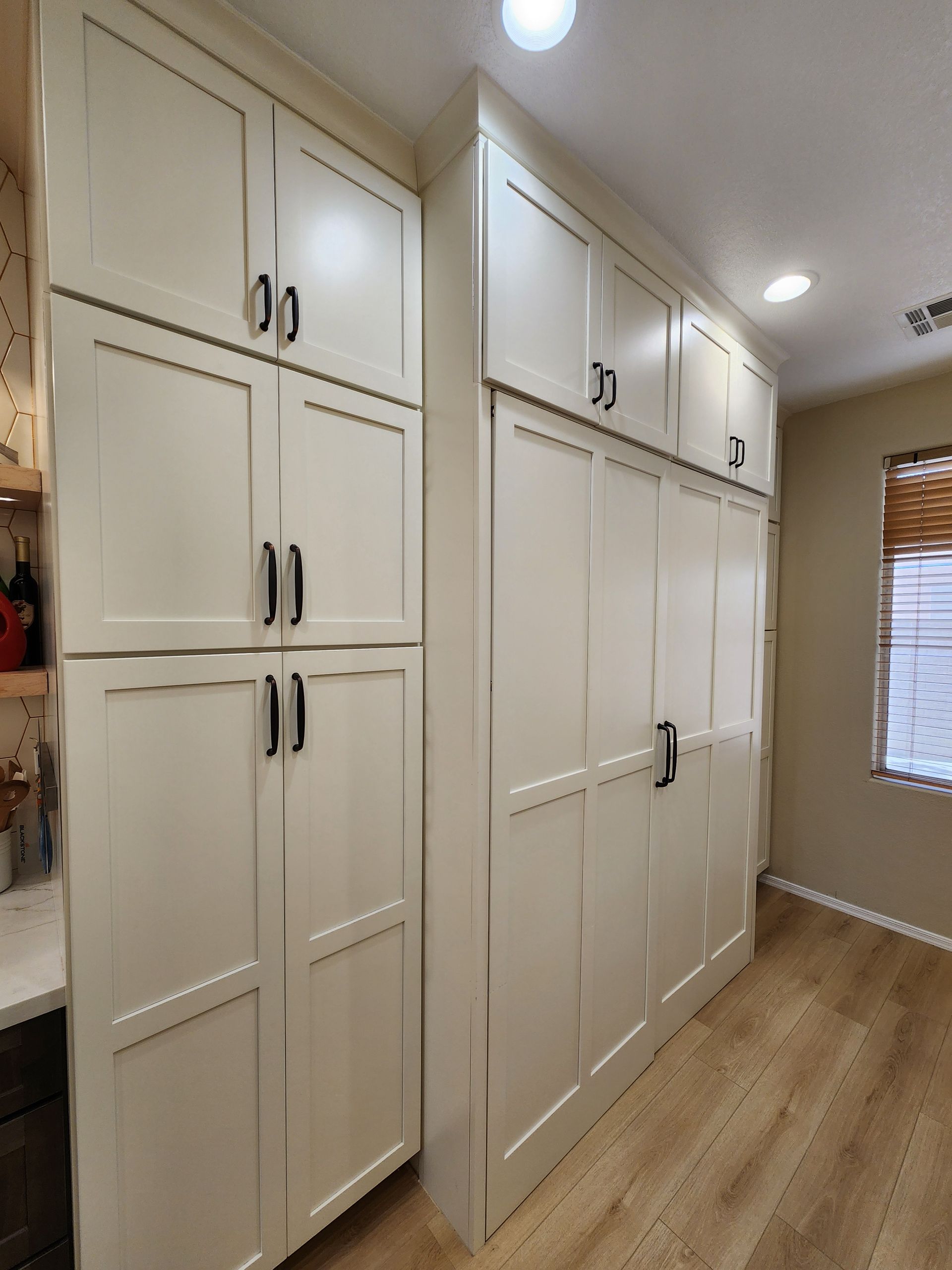 A kitchen with a lot of white cabinets and a window