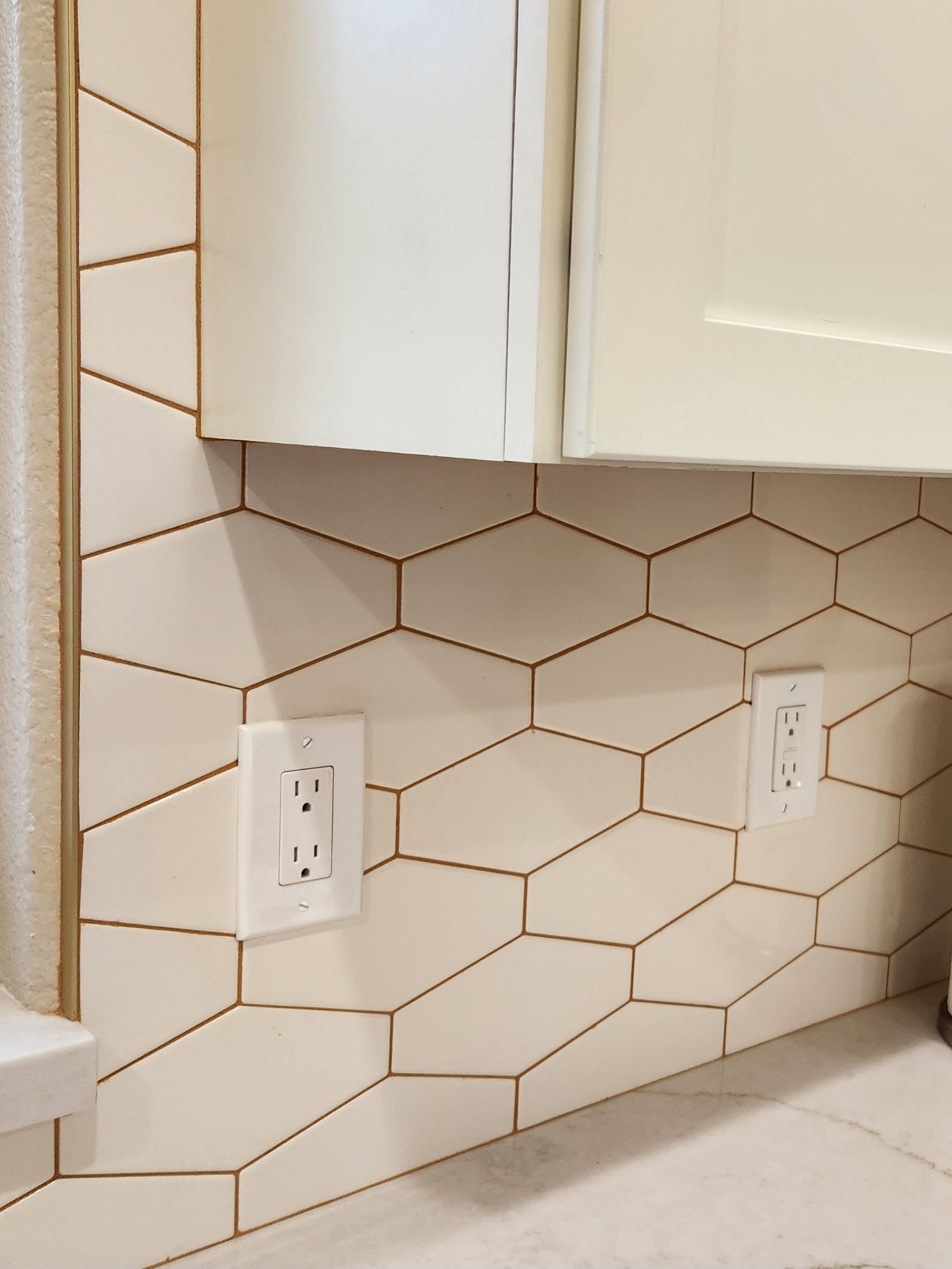 A kitchen with white cabinets and a hexagonal tile wall