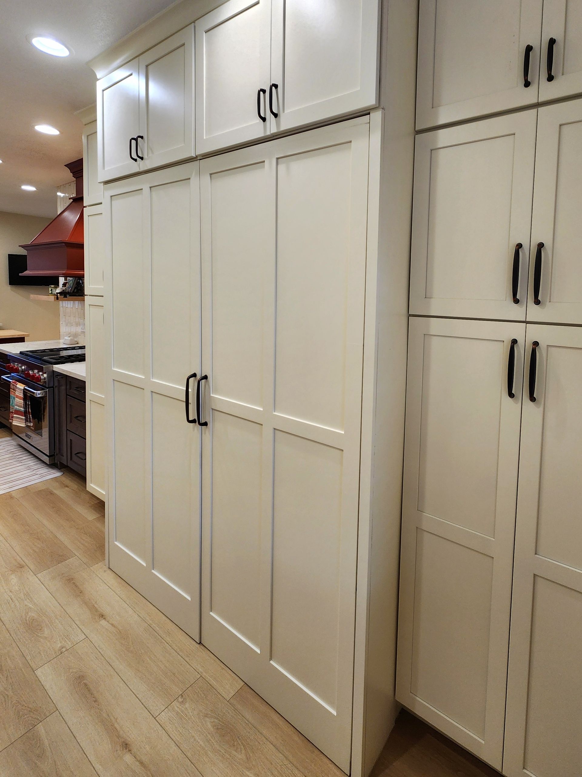A kitchen with lots of white cabinets and wooden floors.