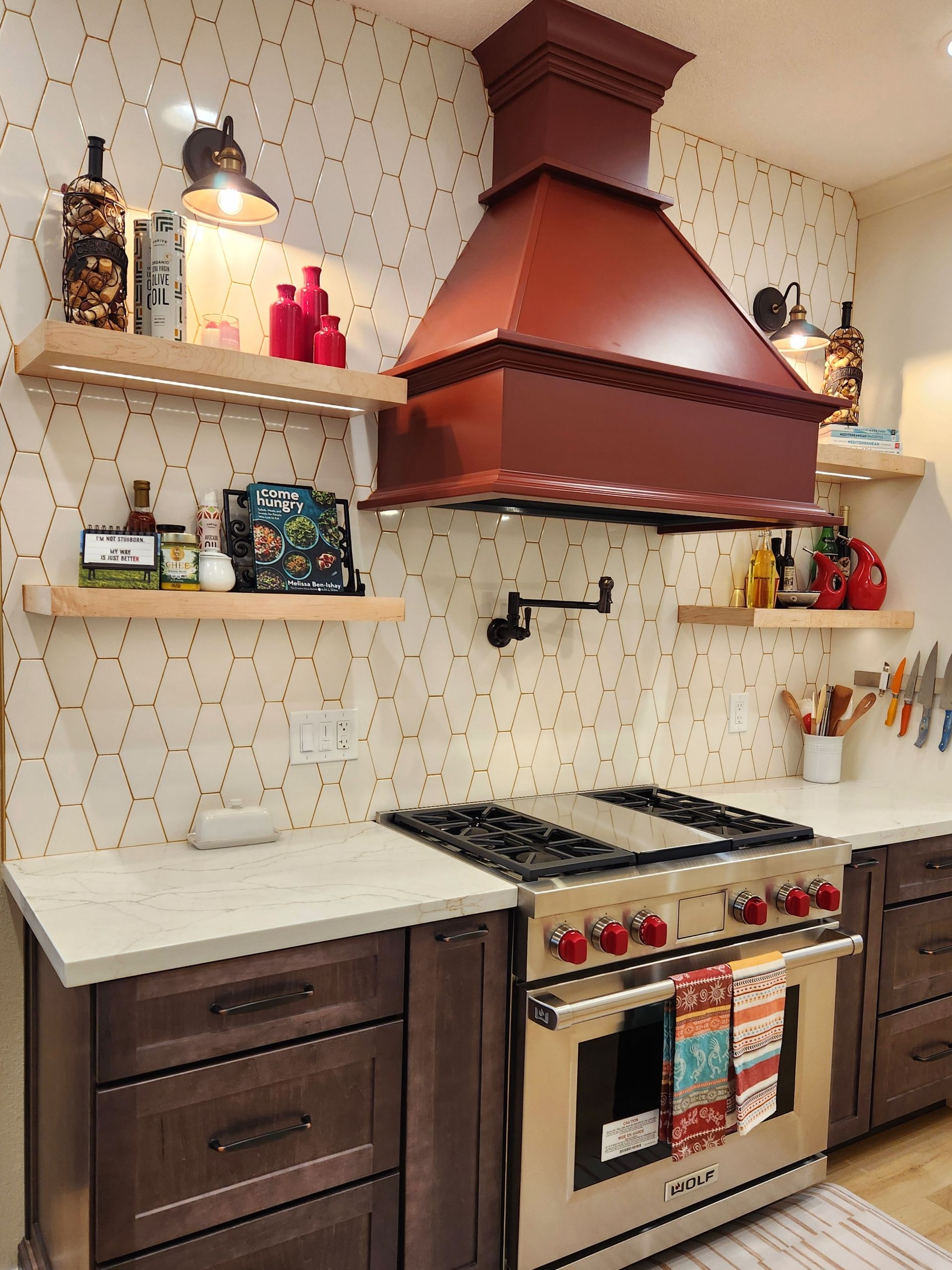 A kitchen with a stove top oven and a red hood