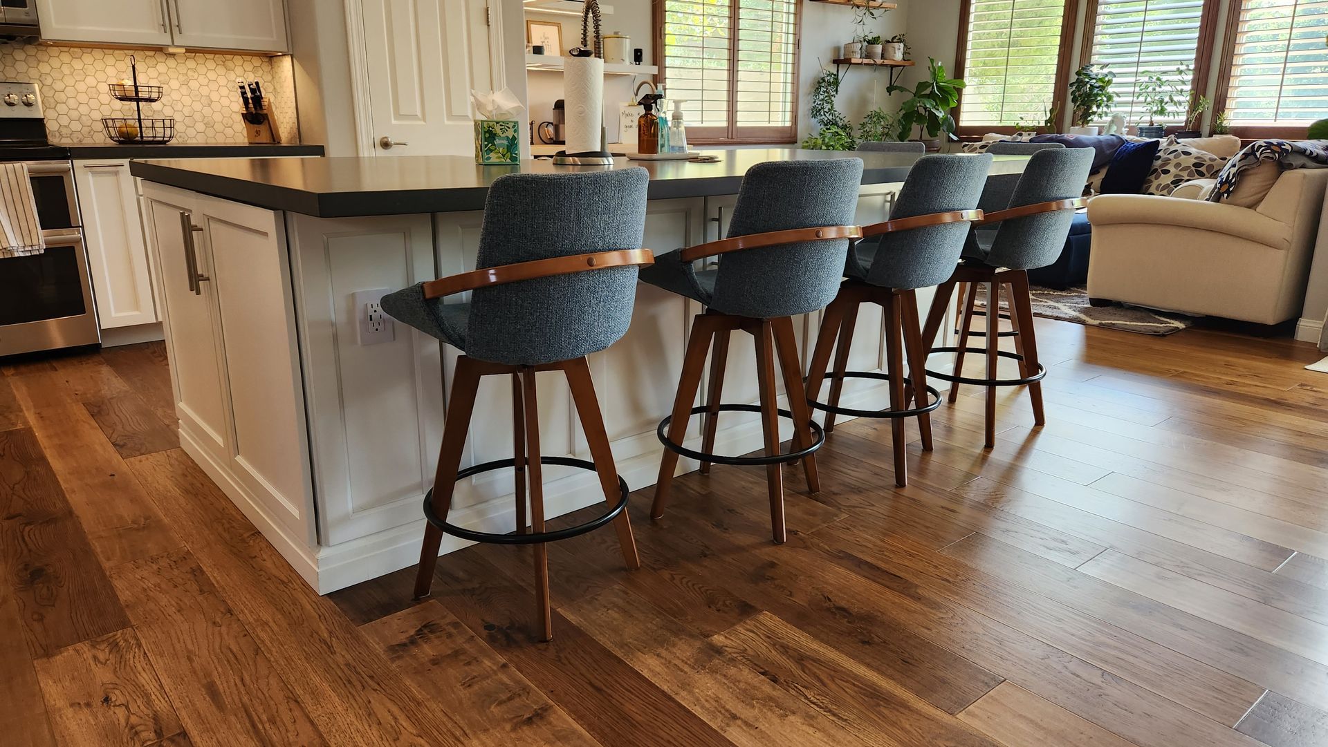A kitchen with a wooden floor and a row of bar stools.