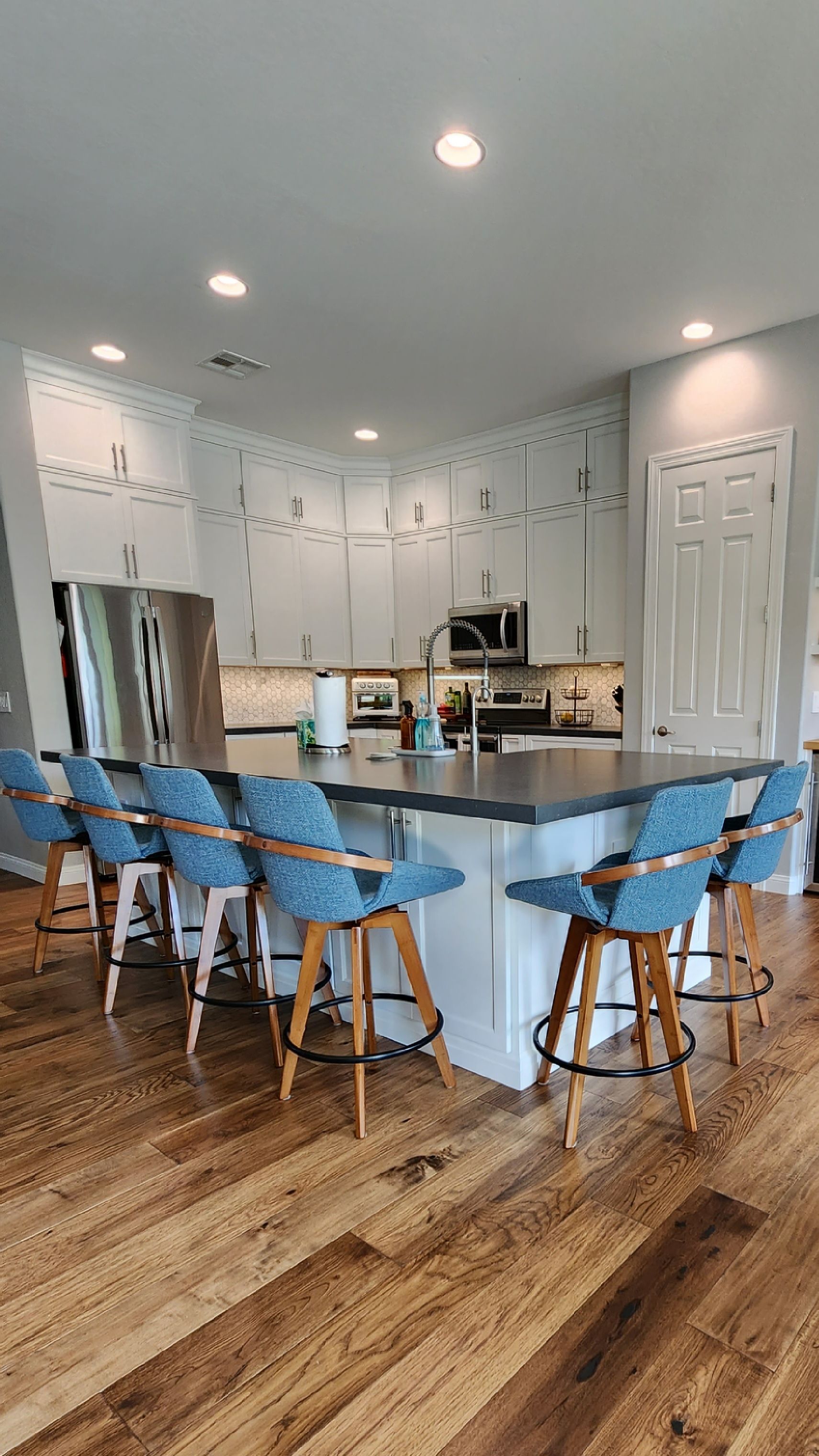 A kitchen with a large island and blue chairs.