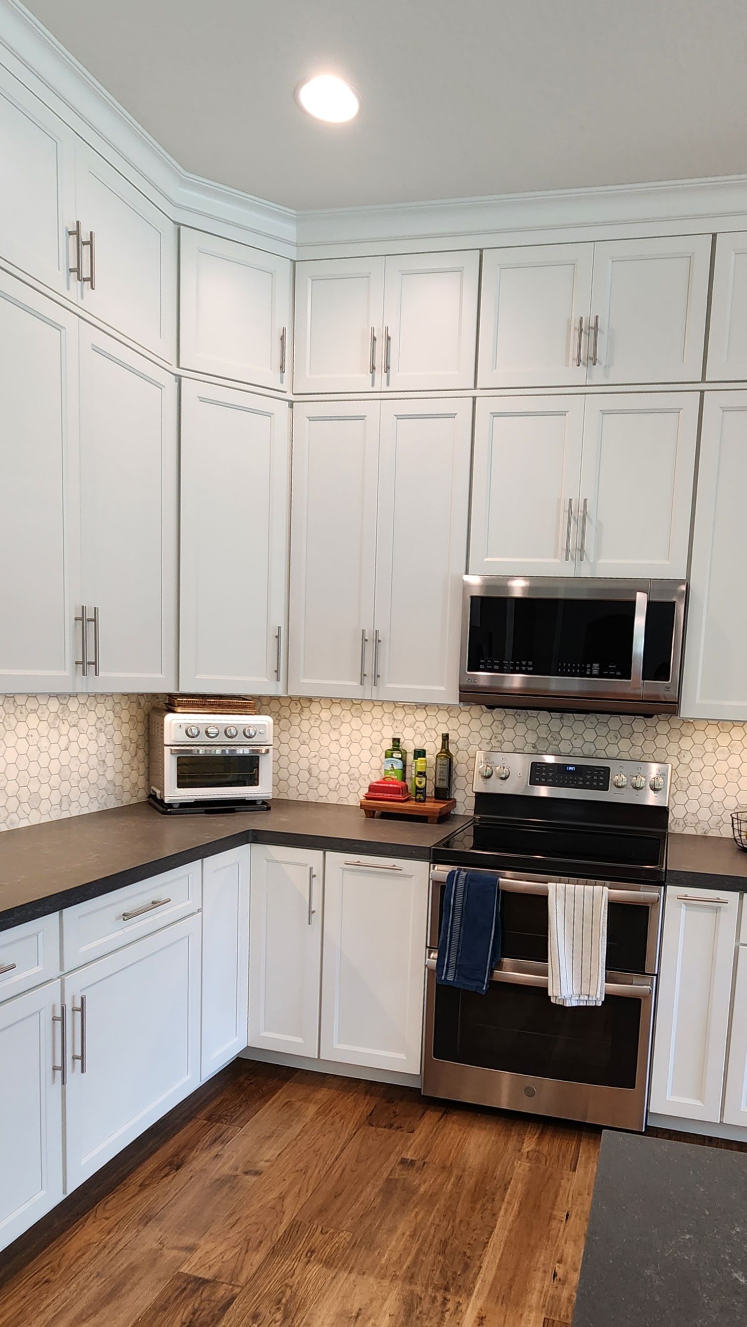 A kitchen with white cabinets, stainless steel appliances, and hardwood floors.