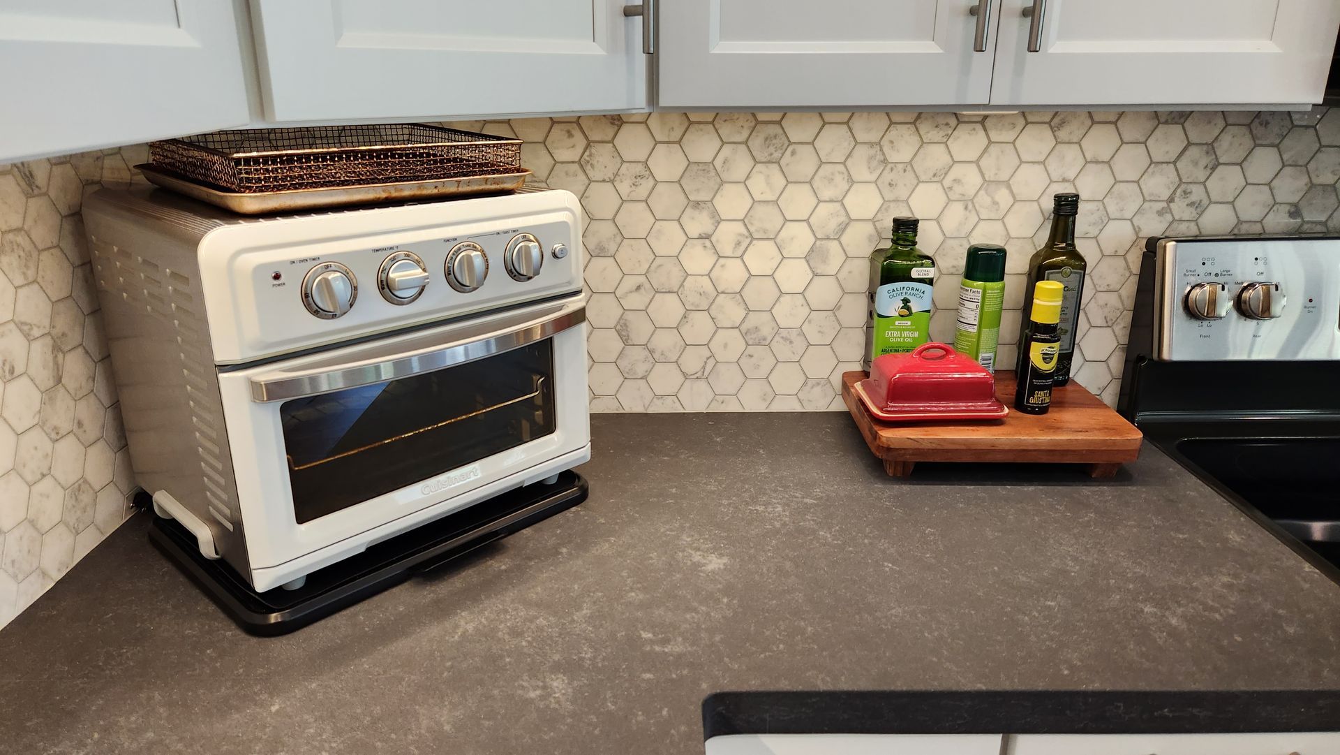 A kitchen with a stove top oven and bottles of olive oil