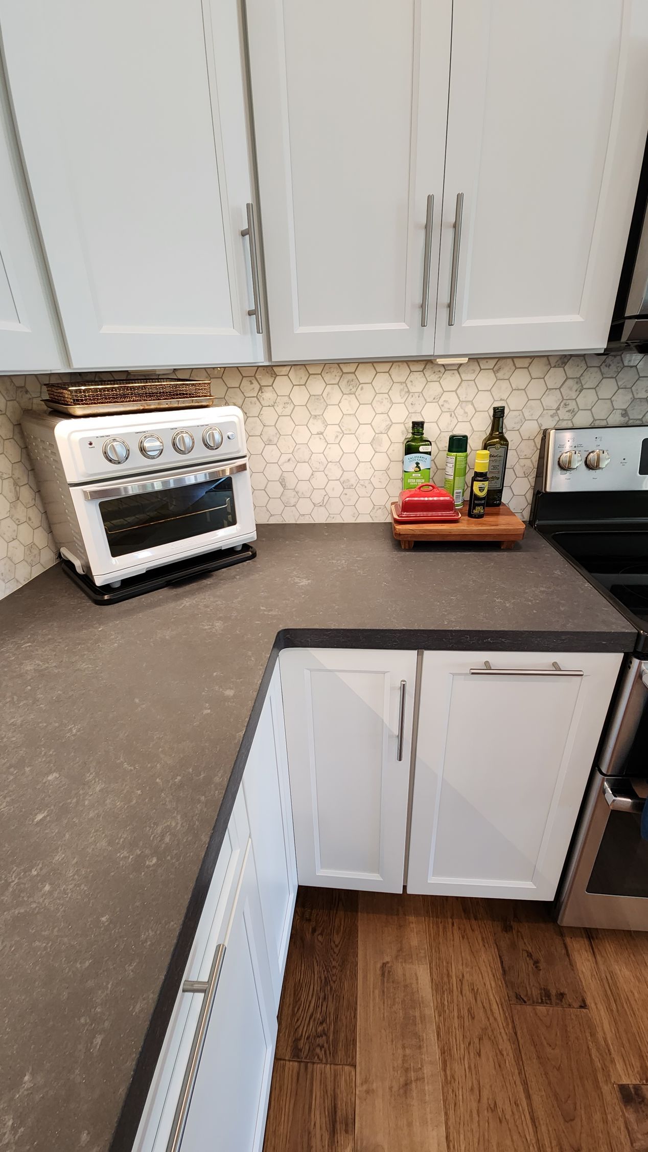 A kitchen with white cabinets, stainless steel appliances, and a stove.